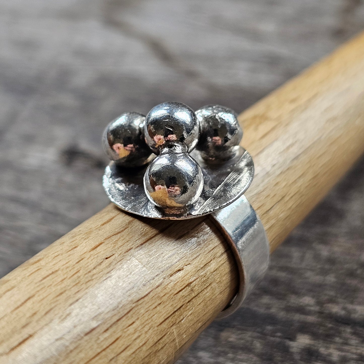 Silver ring with four spherical beads clustered on top.