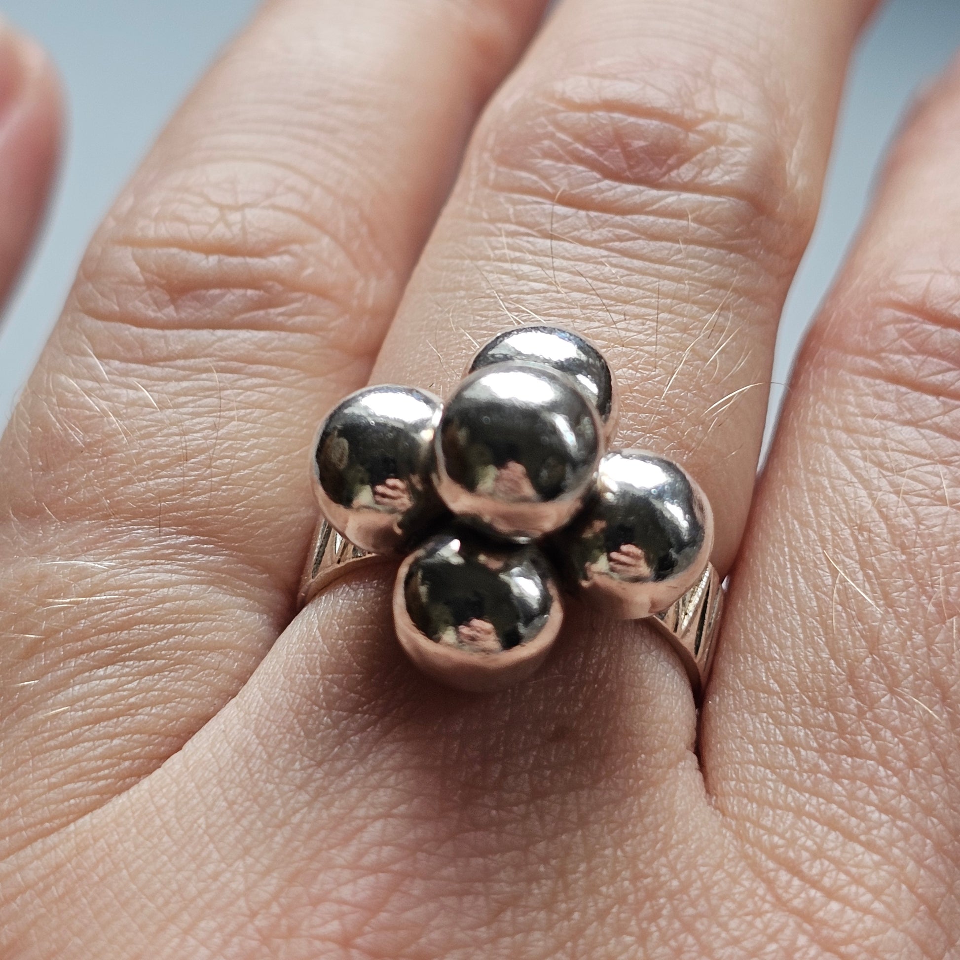 Silver ring with four spherical beads arranged in a clover-like pattern.