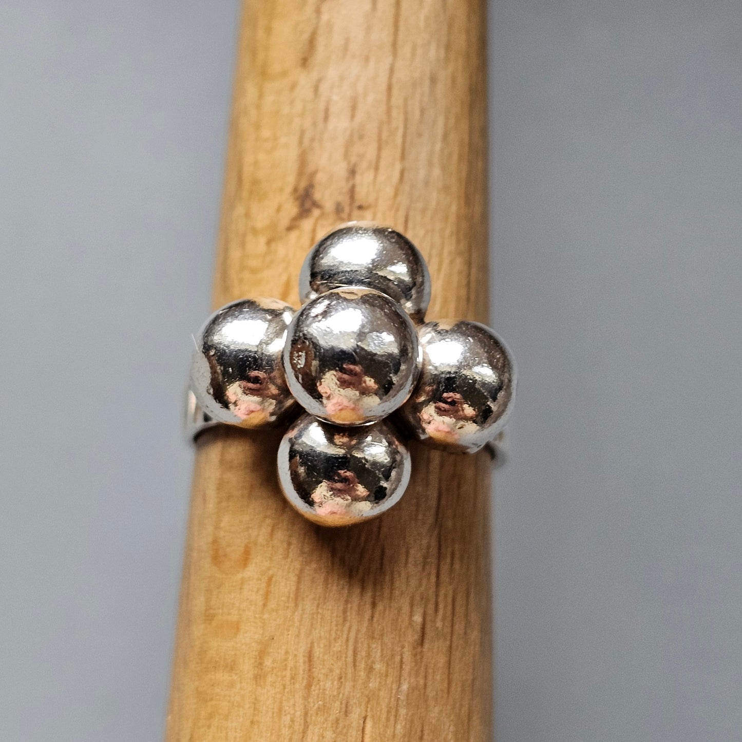 Silver ring with a cluster of spherical beads forming a floral-like design.