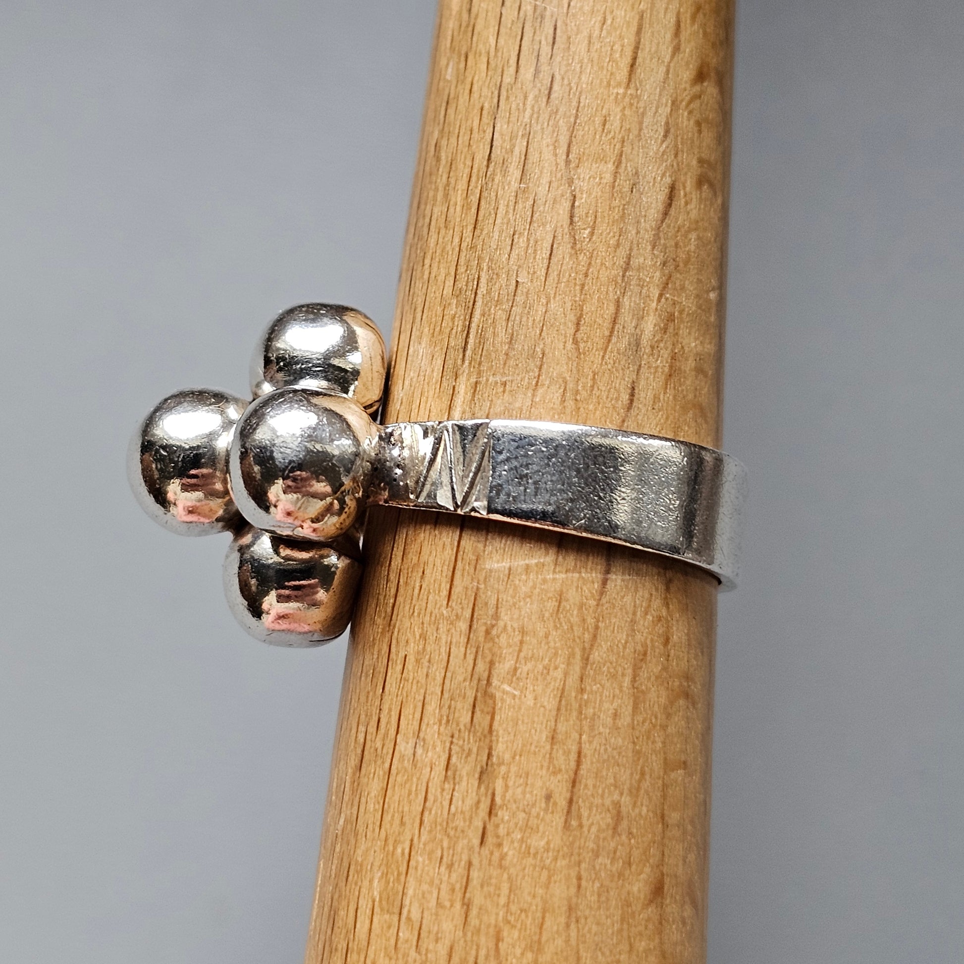 Silver ring with three spherical beads attached to the band.