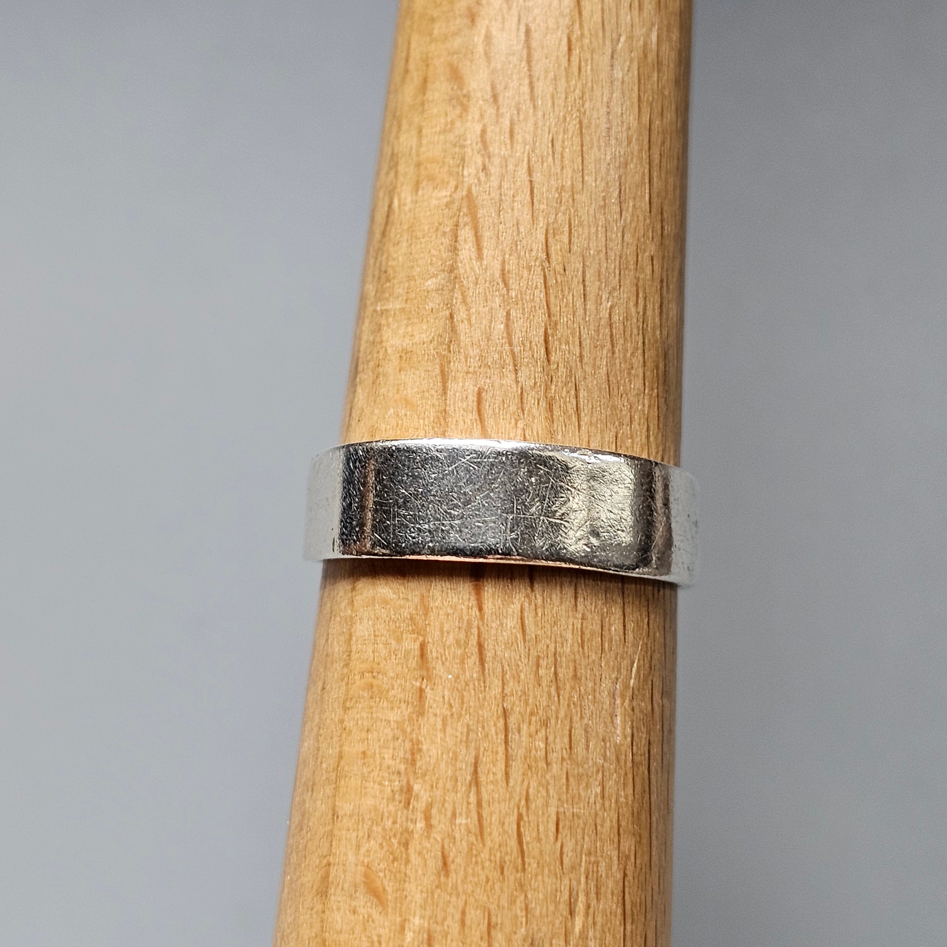 Silver ring on a wooden finger-like surface.