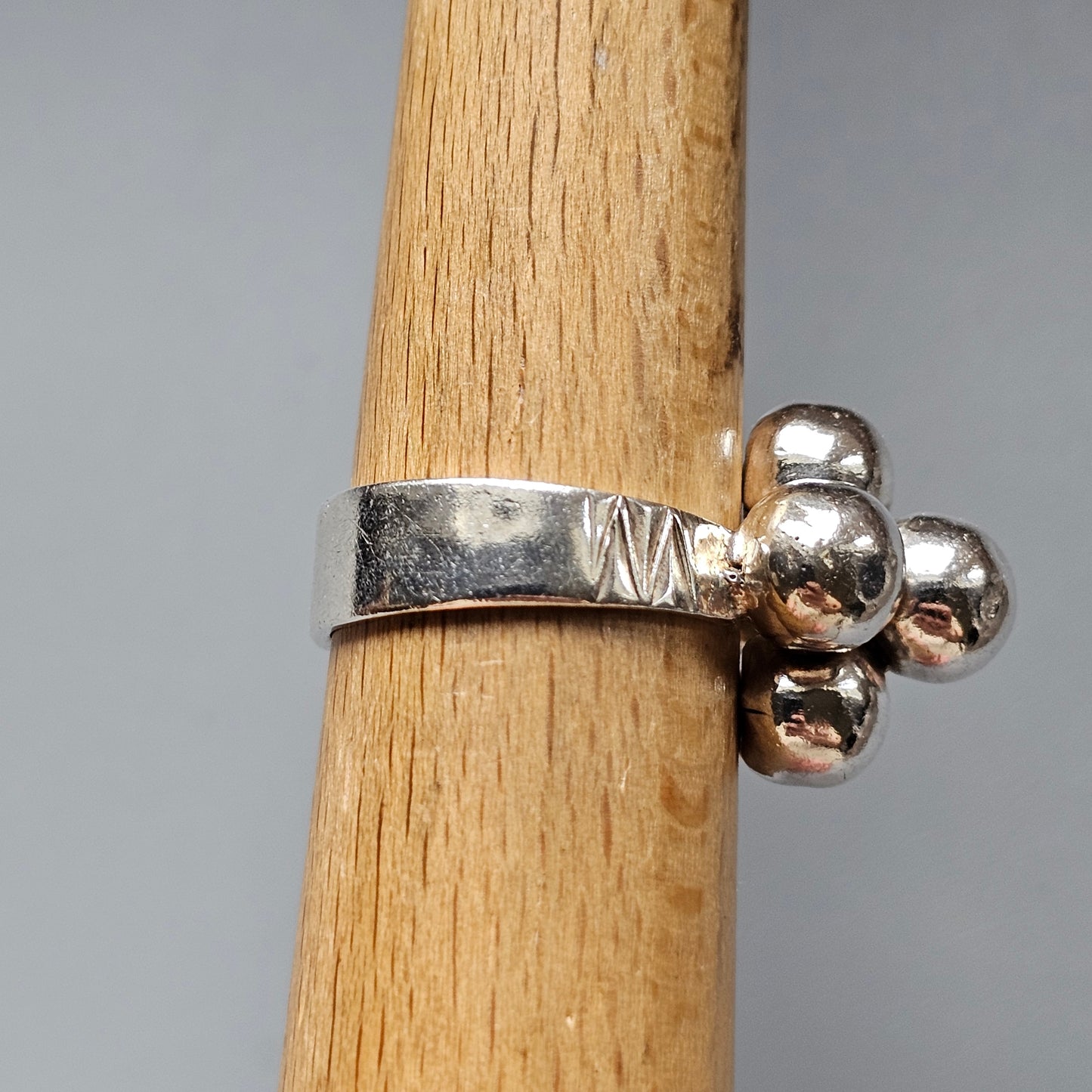 Silver ring with a cluster of small spherical beads on one side.