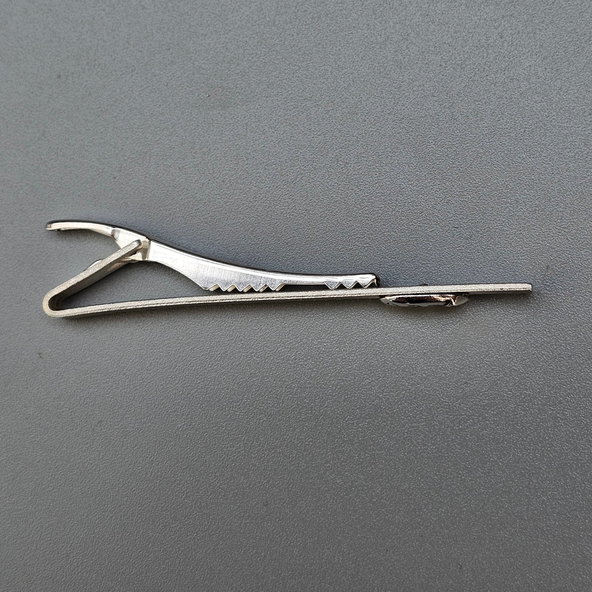 Surgical clamp or forceps with a locking mechanism and serrated jaws.