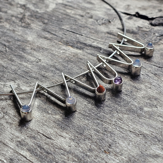 Set of silver stud earrings with colorful gemstones arranged in a zigzag pattern.