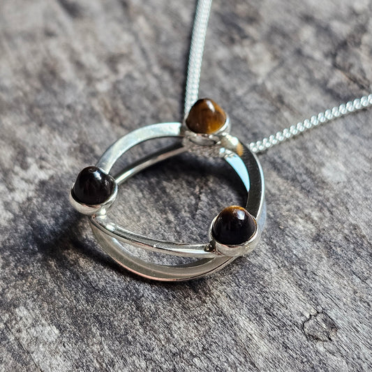 Silver pendant necklace featuring a circular design with three small gemstones.