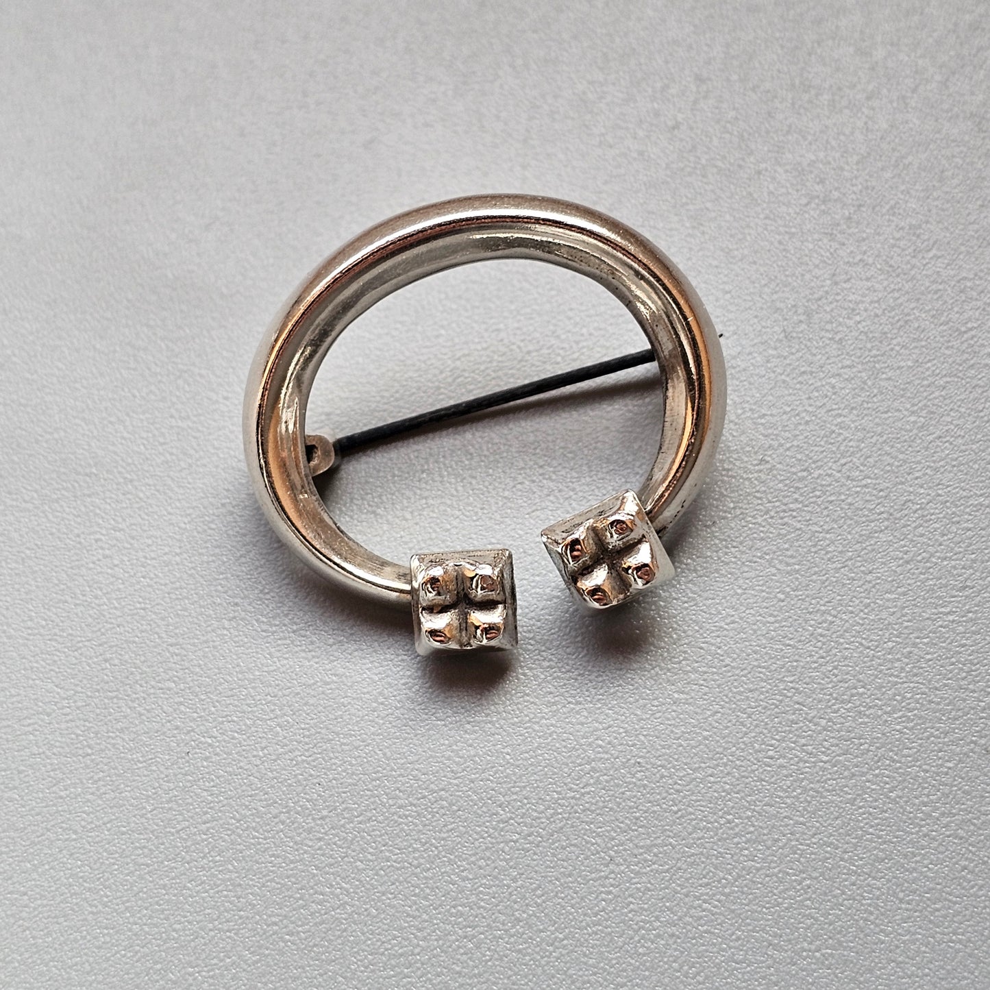 Circular silver body piercing jewelry with decorative ends and a straight bar through the center.