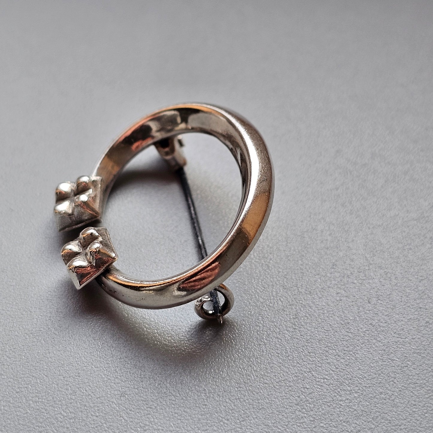 Silver ring with three small prongs and a dangling loop attachment.