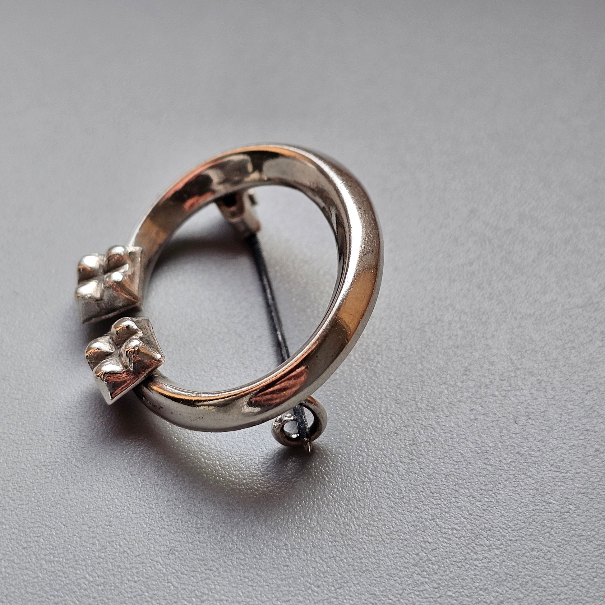 Silver ring with three small prongs and a dangling loop attachment.