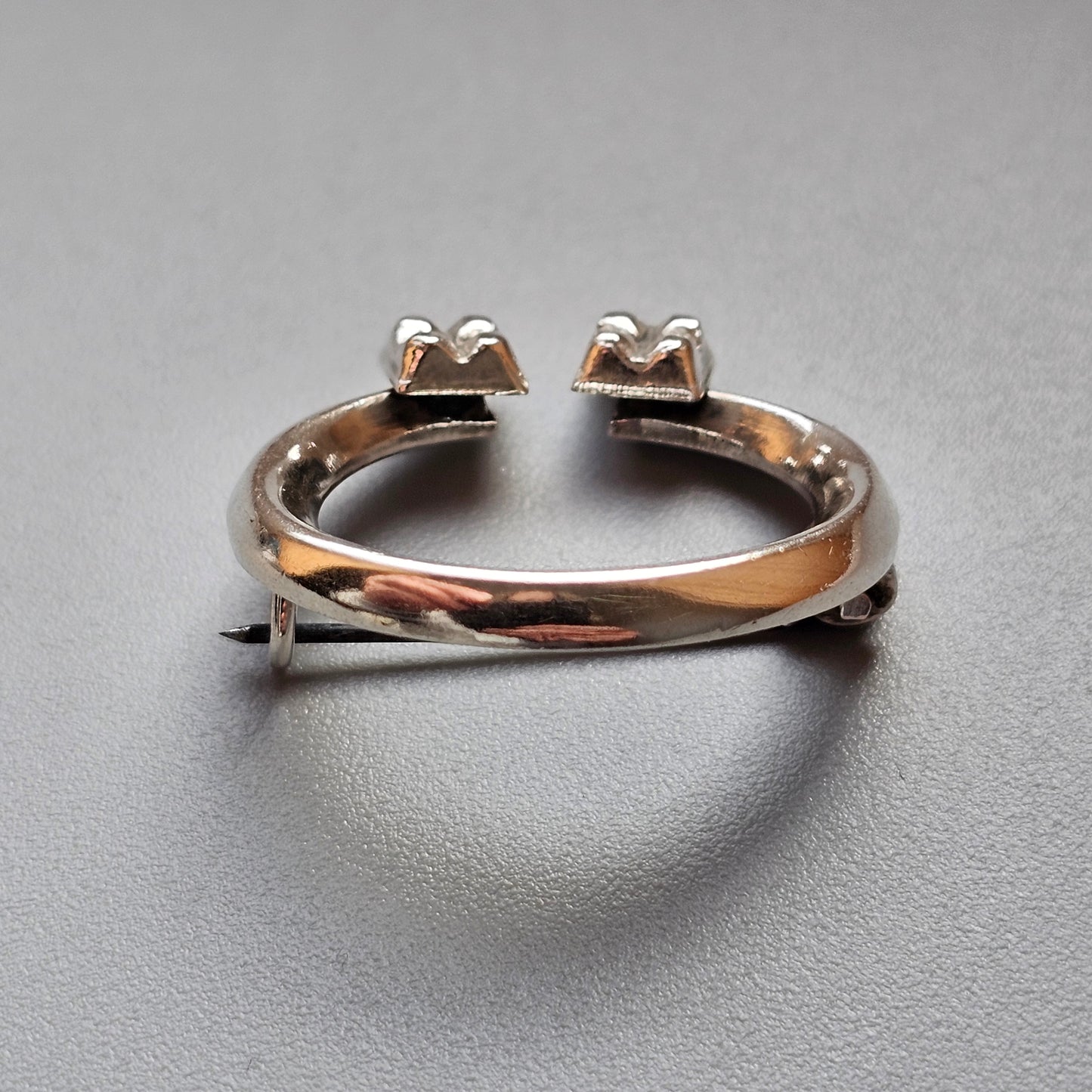 Open-ended silver ring with two pairs of prongs at each end.