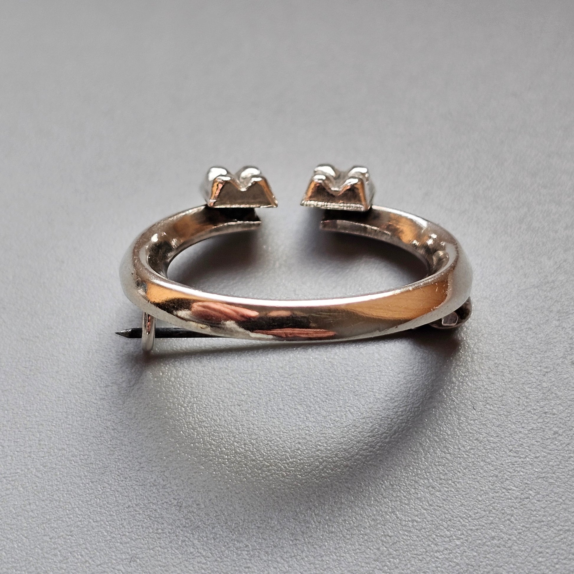 Open-ended silver ring with two pairs of prongs at each end.