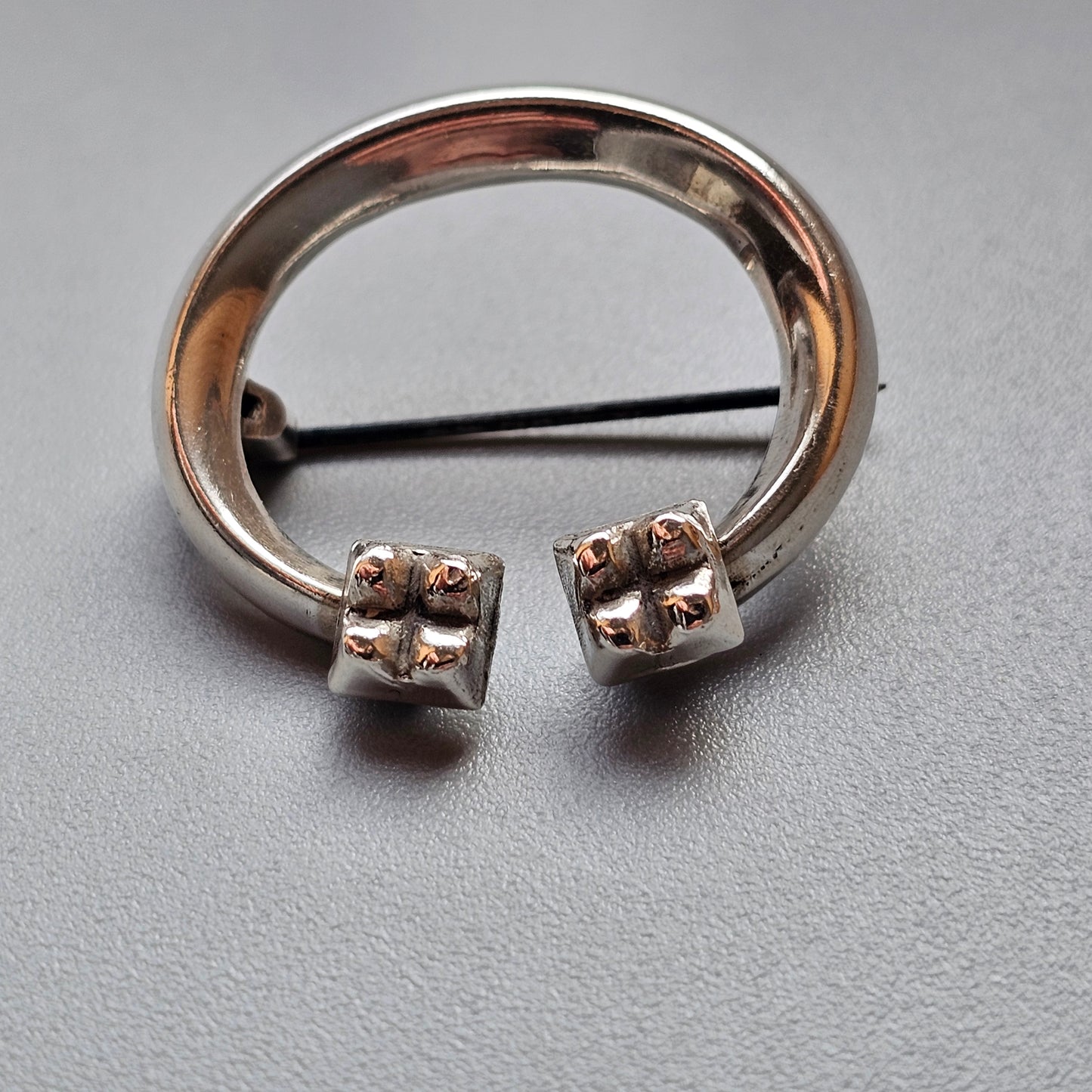 Horseshoe-shaped silver piercing jewelry with cube-like ends featuring small spheres.