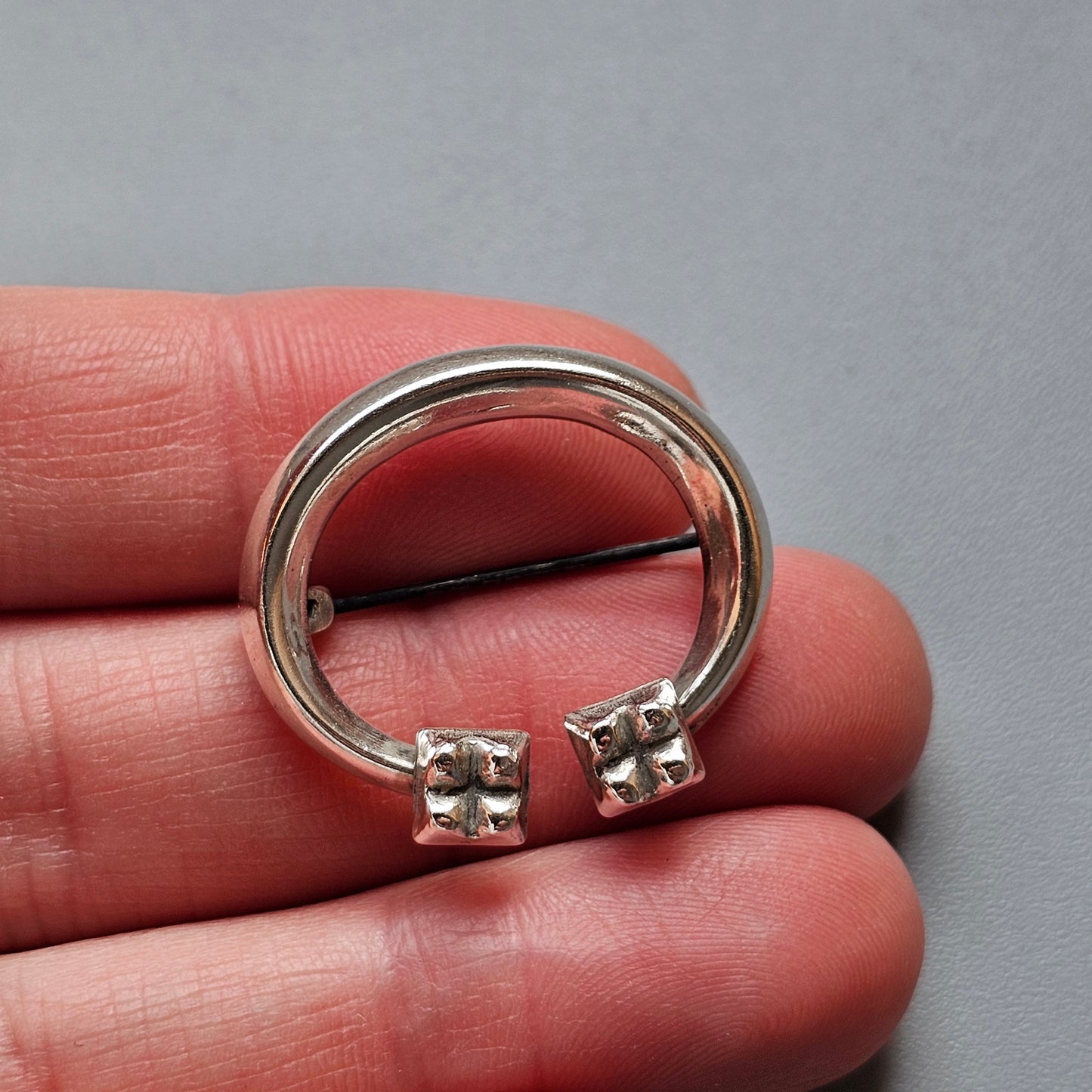 Silver horseshoe-shaped piercing with decorative ends.