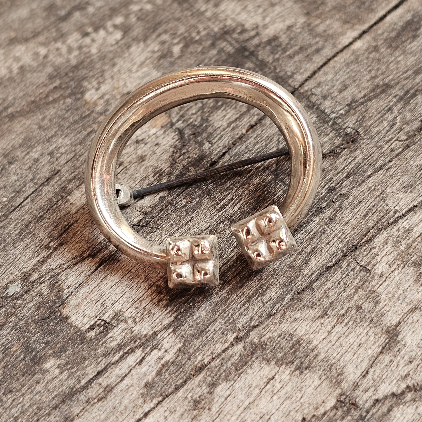 Silver brooch with two decorative cube-shaped beads on its band.