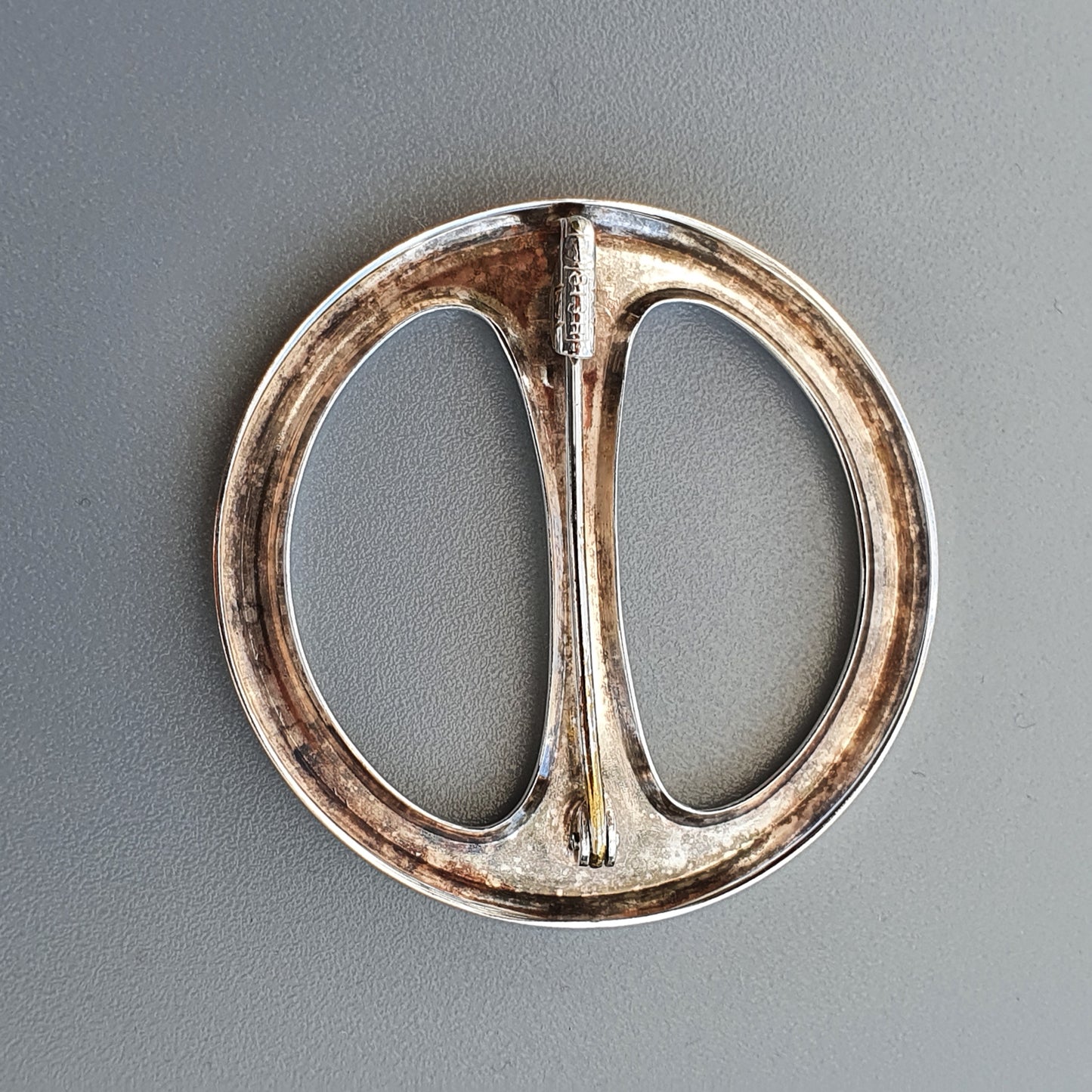 Circular metal belt buckle with a central divider.