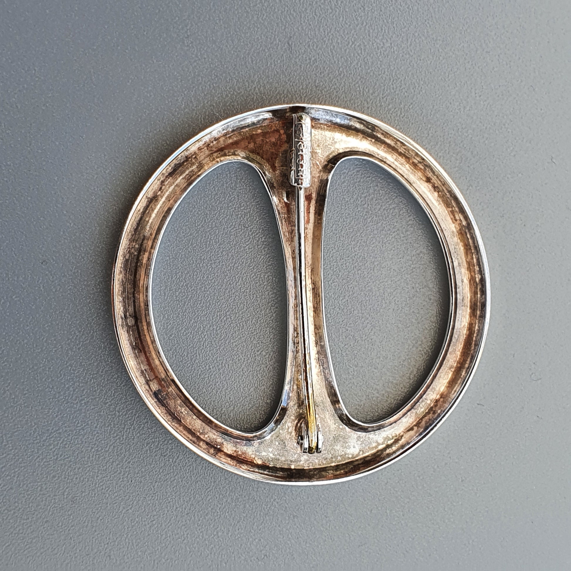 Circular metal belt buckle with a central divider.