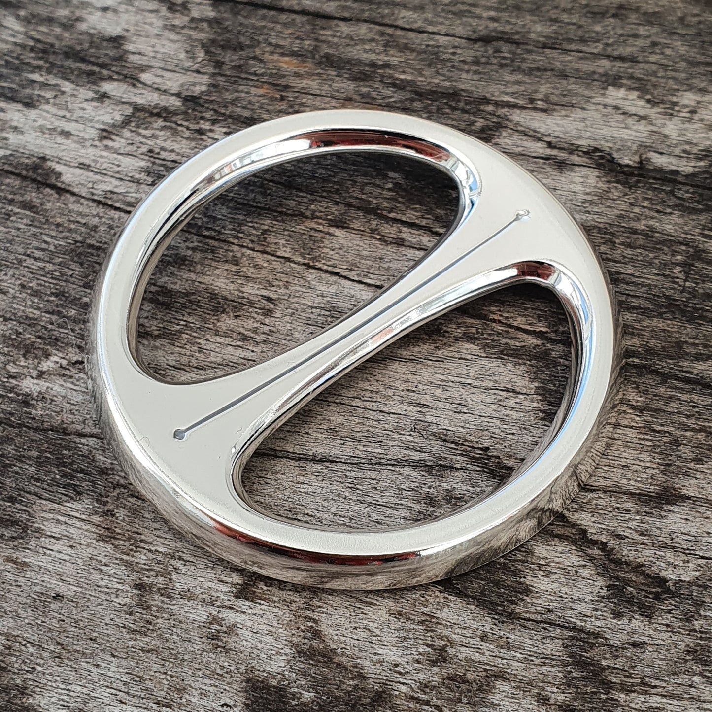 Shiny silver-colored metal scarf ring with a curved S-shaped design.