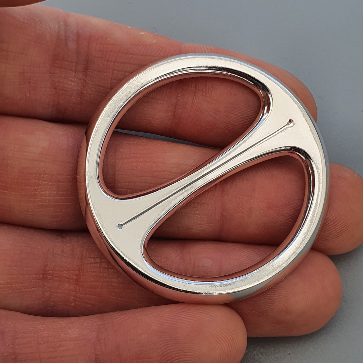 Circular silver-colored metal object with an S-shaped divider in the center.