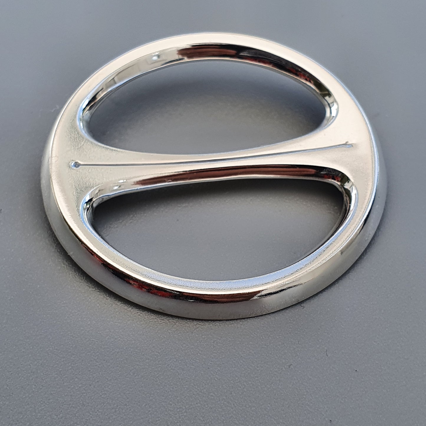 Shiny metallic oval-shaped object with two symmetrical openings.