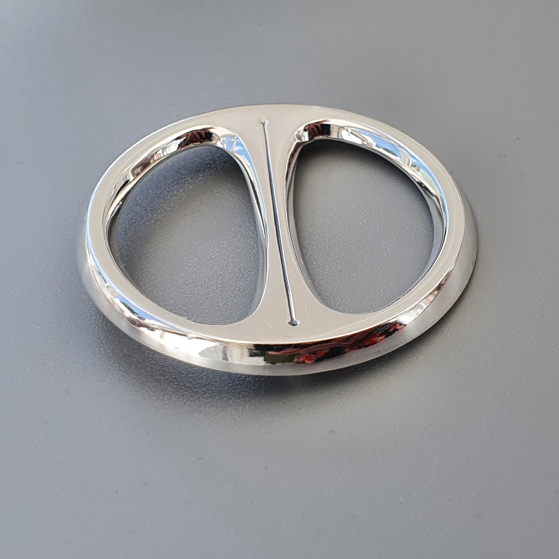 Shiny metal belt buckle with two oval openings separated by a central bar.