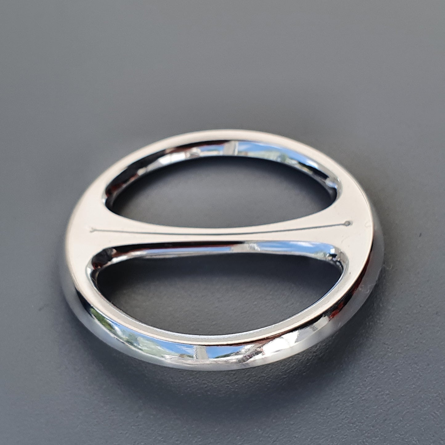 Silver ring with two oval openings separated by a central bar.