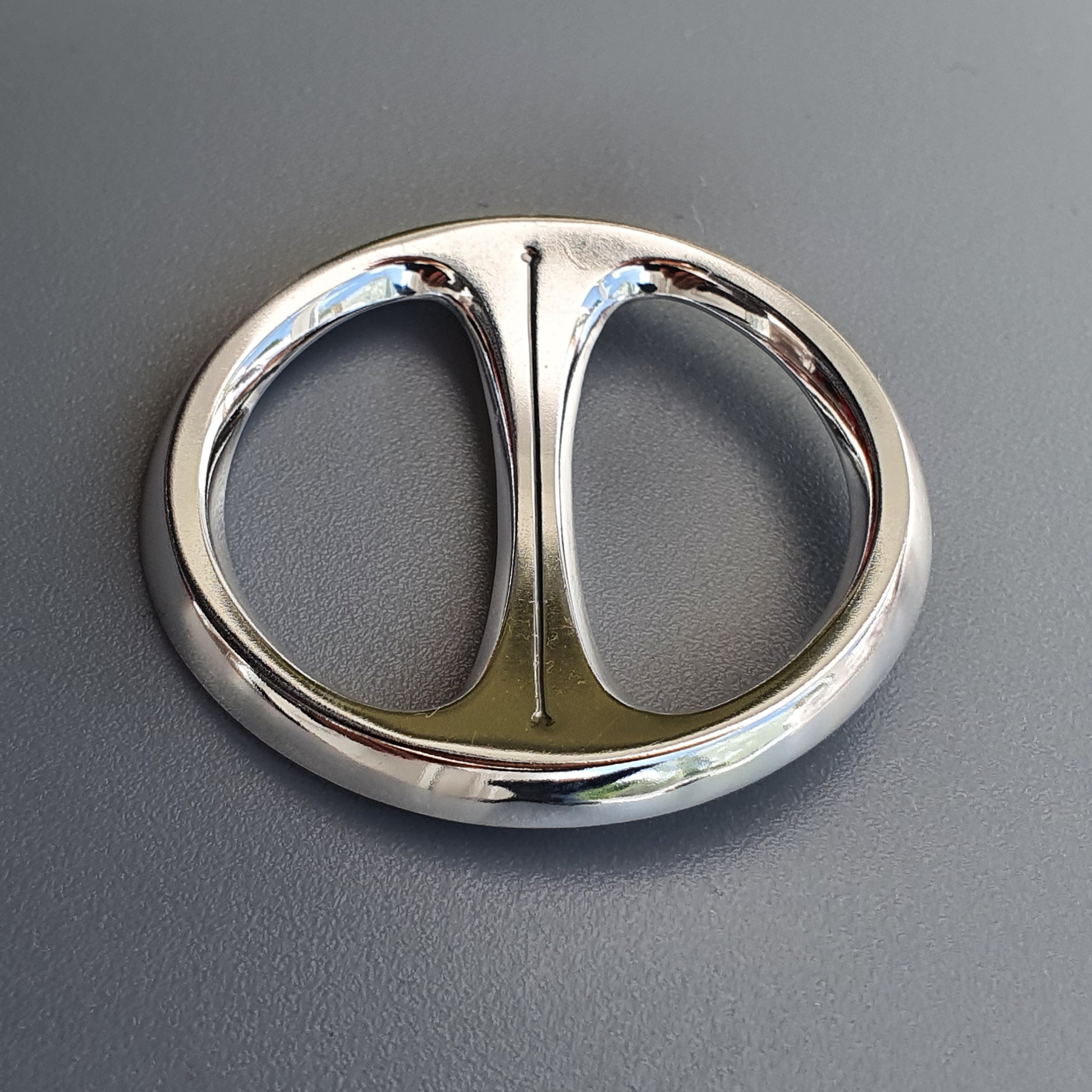 Circular silver-colored metal buckle with two symmetrical openings divided by a central bar.