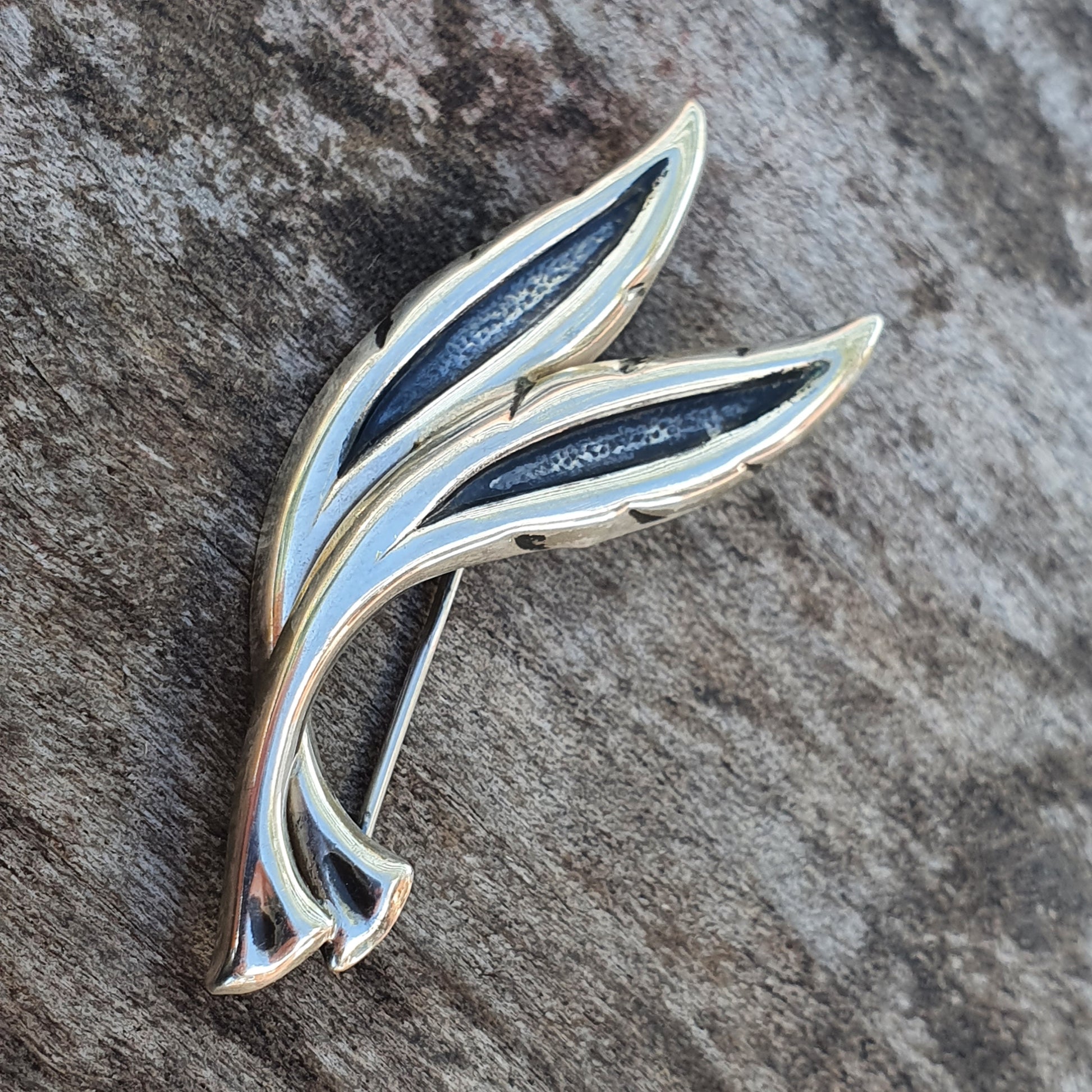 Elegant leaf-shaped brooch or pin with blue enamel inlay and silver-toned metal edges.