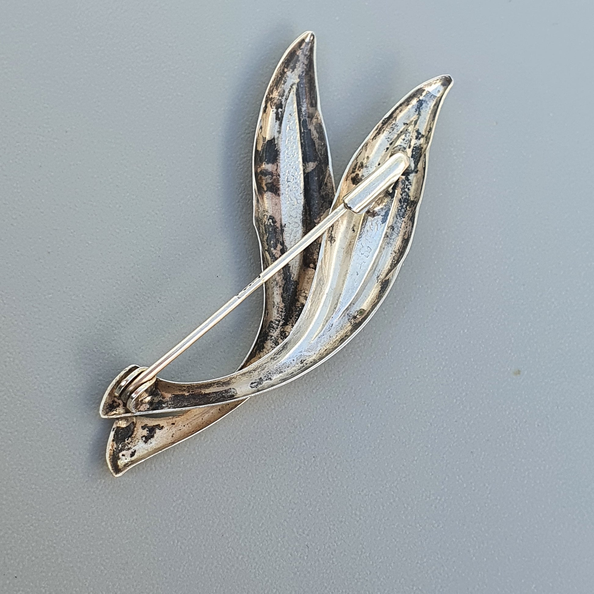 Silver brooch shaped like stylized leaves or petals.