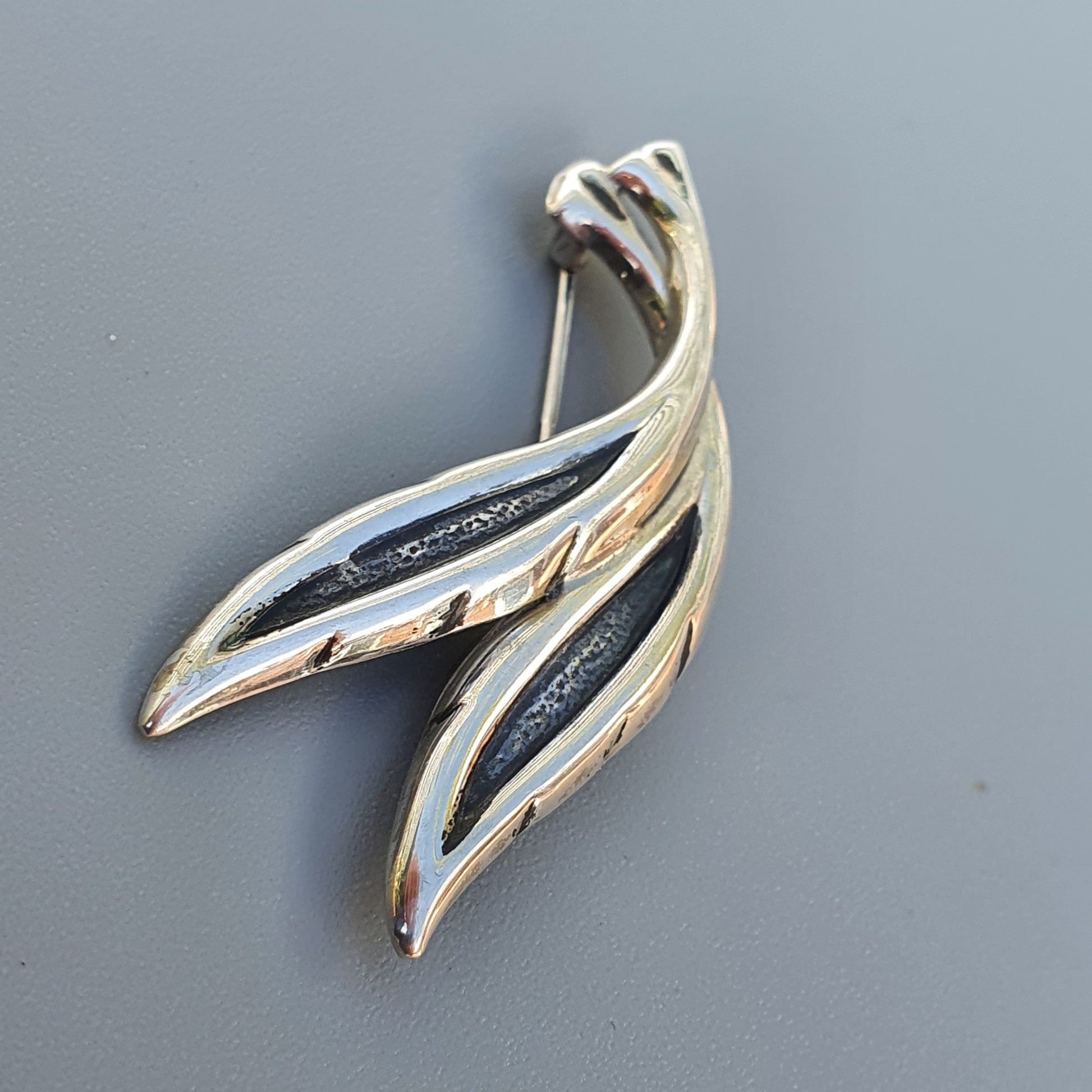 Stylized silver brooch or pendant shaped like an abstract bird or flame.