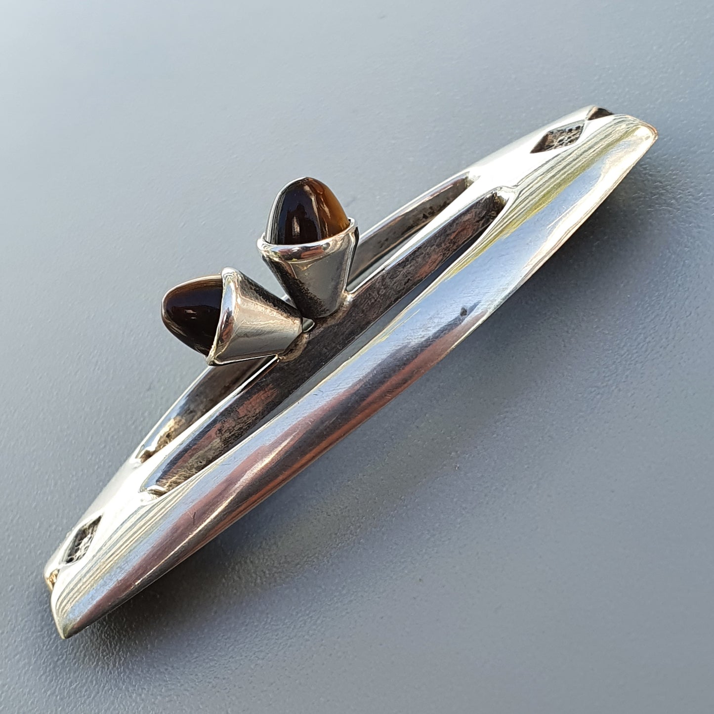 Sleek, chrome-plated vintage car hood ornament with two amber-colored glass or crystal accents.