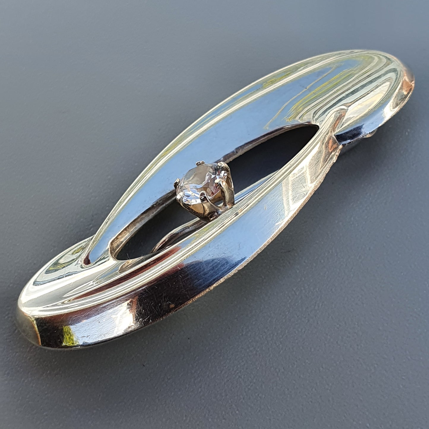 Sleek, elongated silver brooch with blue enamel accents and a central diamond.