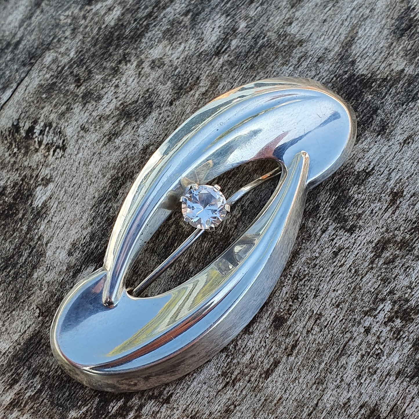 Sleek, modern silver ring with a curved design and a single diamond accent.