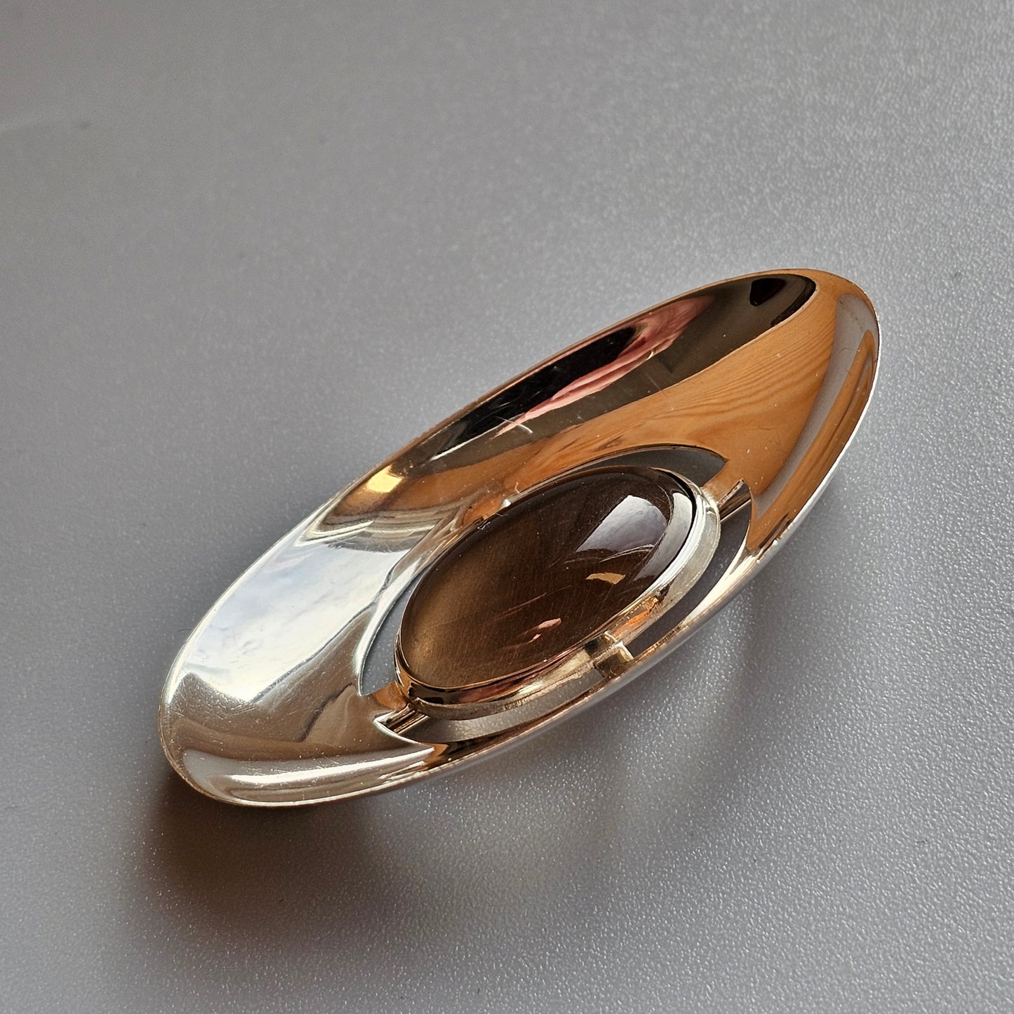 Oval-shaped glass or crystal paperweight with a golden-amber hue.