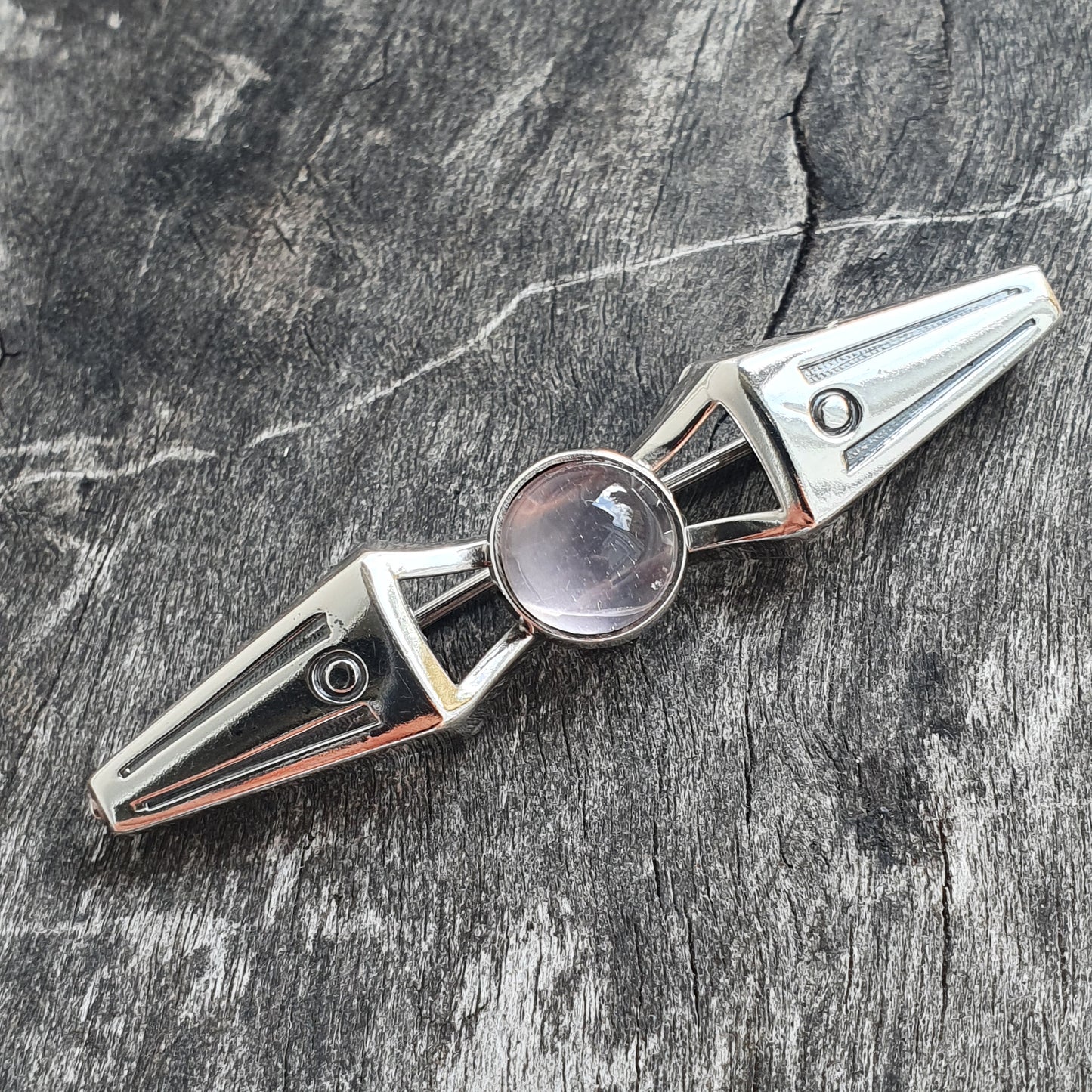 Silver geometric pendant with a central clear gemstone or crystal.