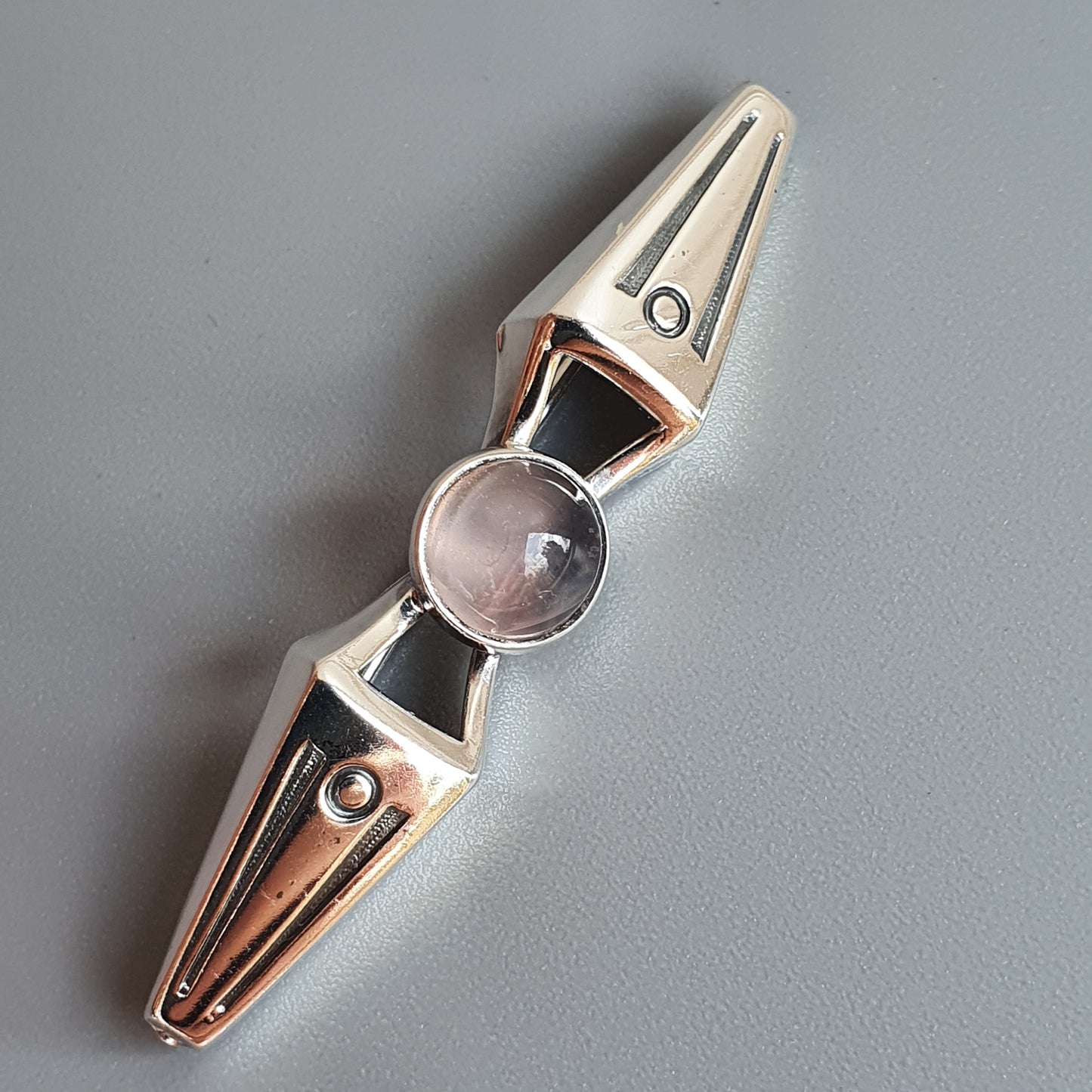 Metallic fidget spinner with a central glass or crystal-like element.