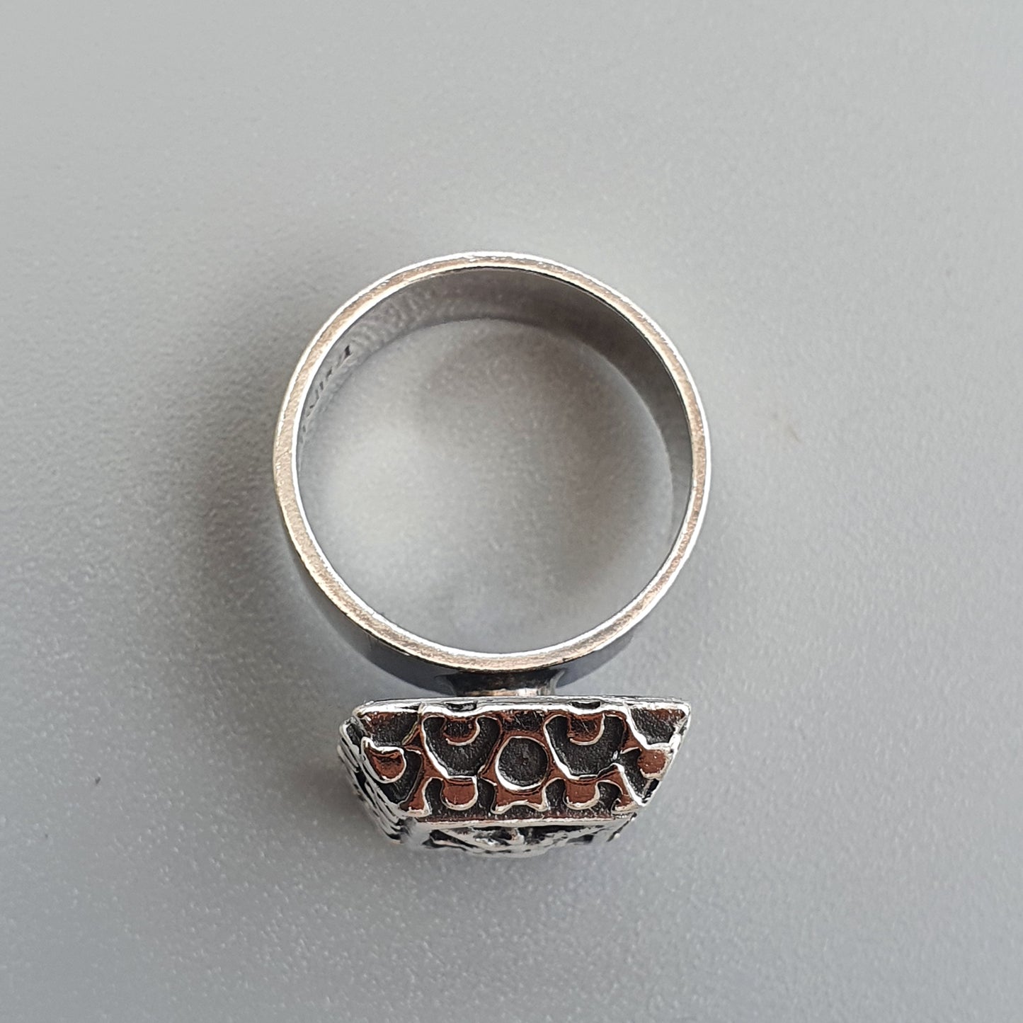 Silver ring with an ornate, textured half-dome design attached to the band.