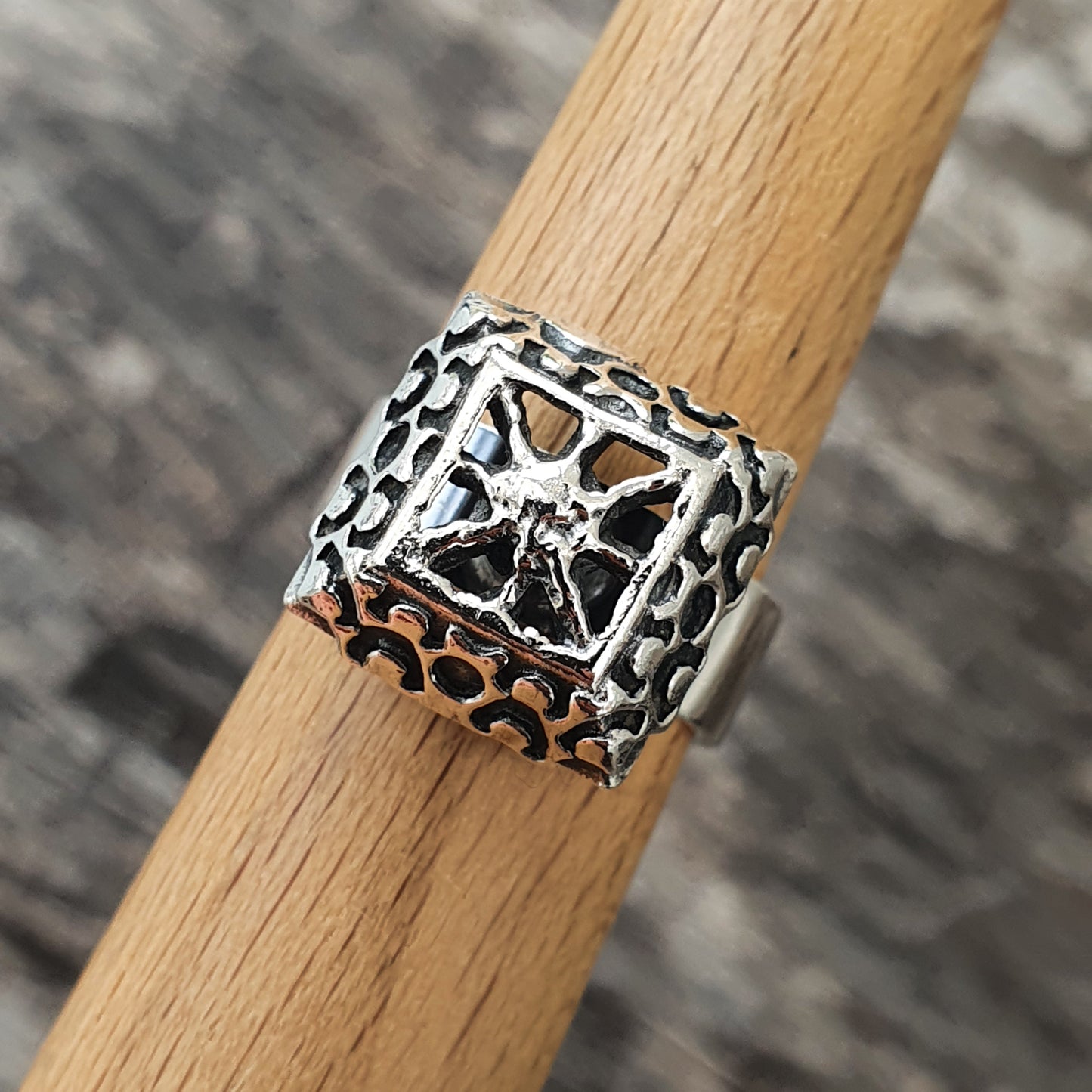 Ornate silver ring with a cross-shaped design and textured details.