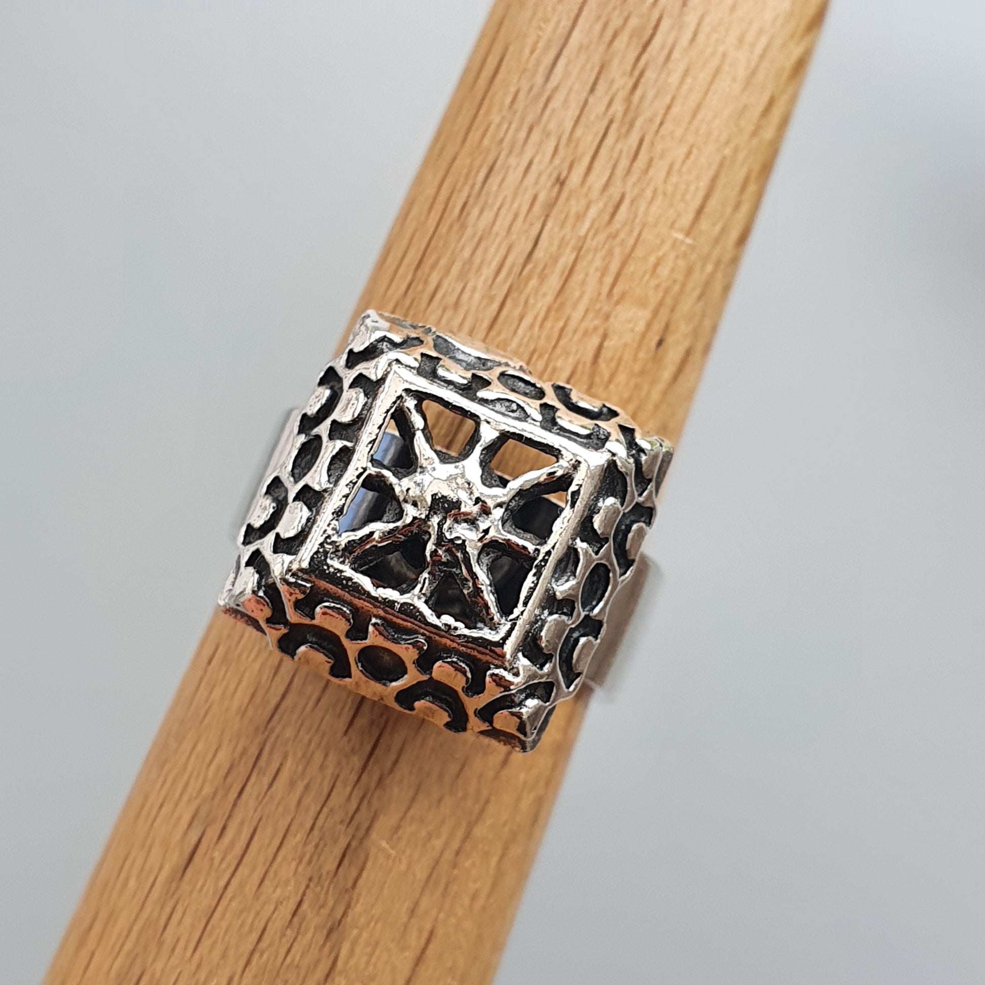 Ornate silver ring with a textured square design on top.