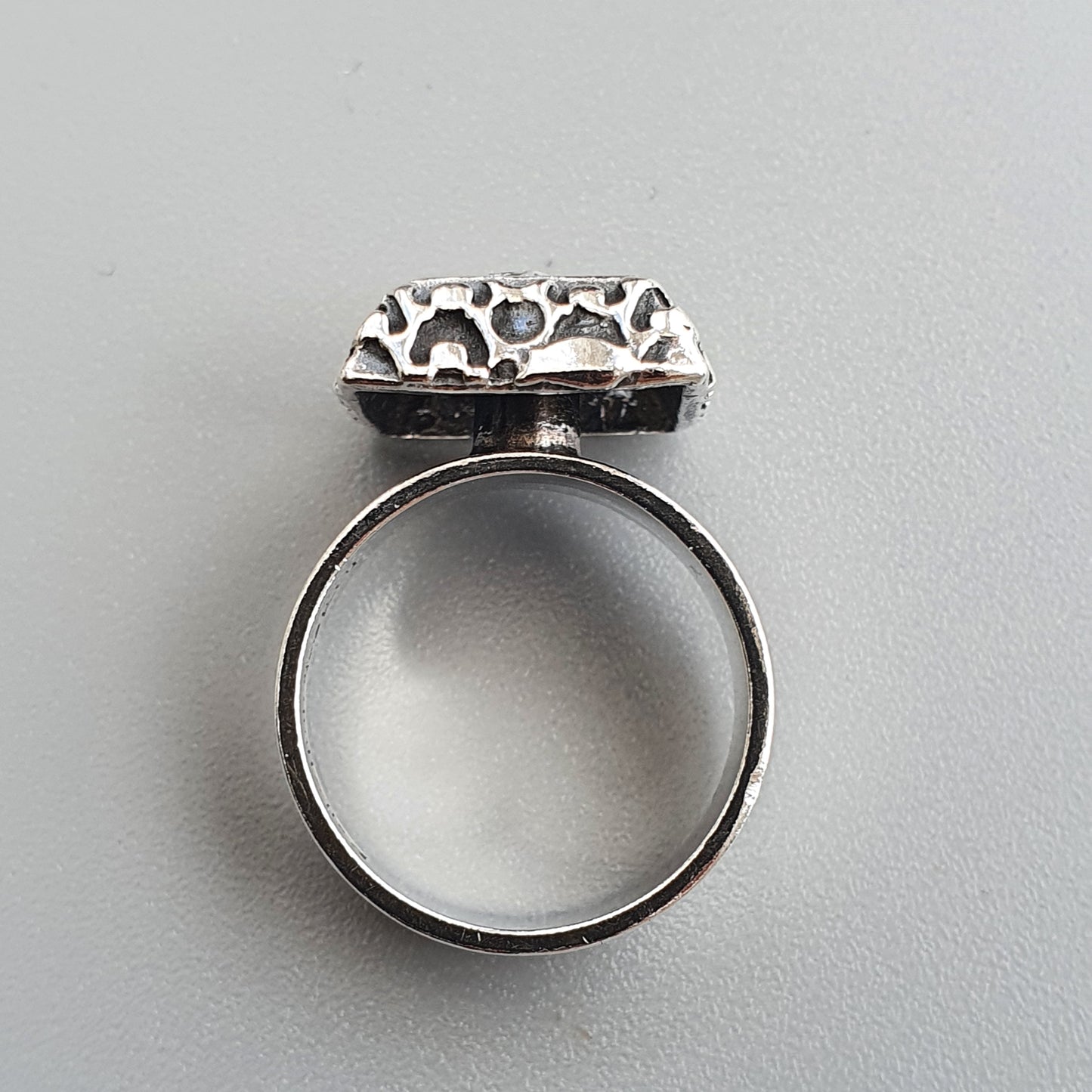 Silver ring with an ornate square-shaped top featuring a filigree or openwork design.