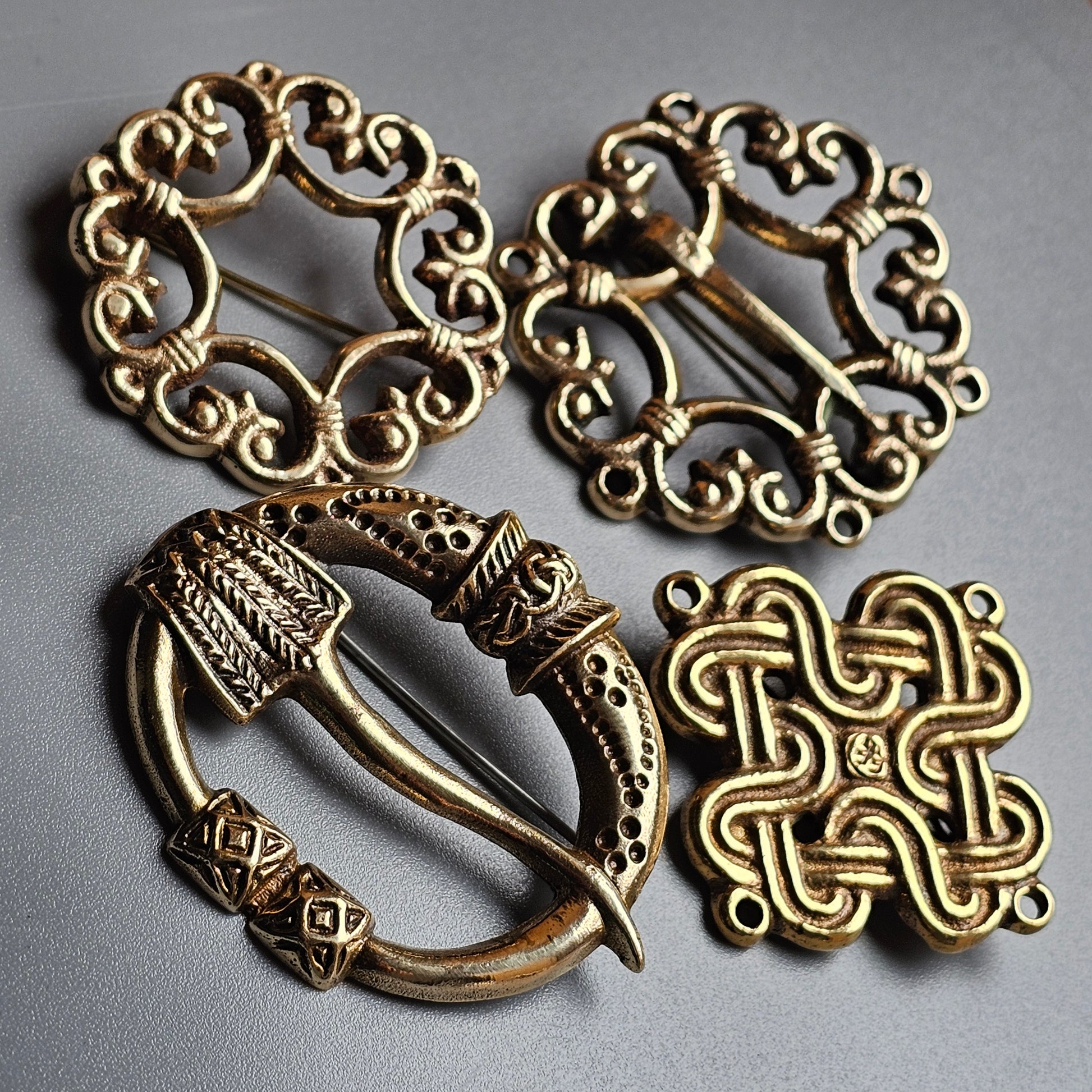 Ornate gold-toned metal brooches or clasps with intricate Celtic-inspired designs.