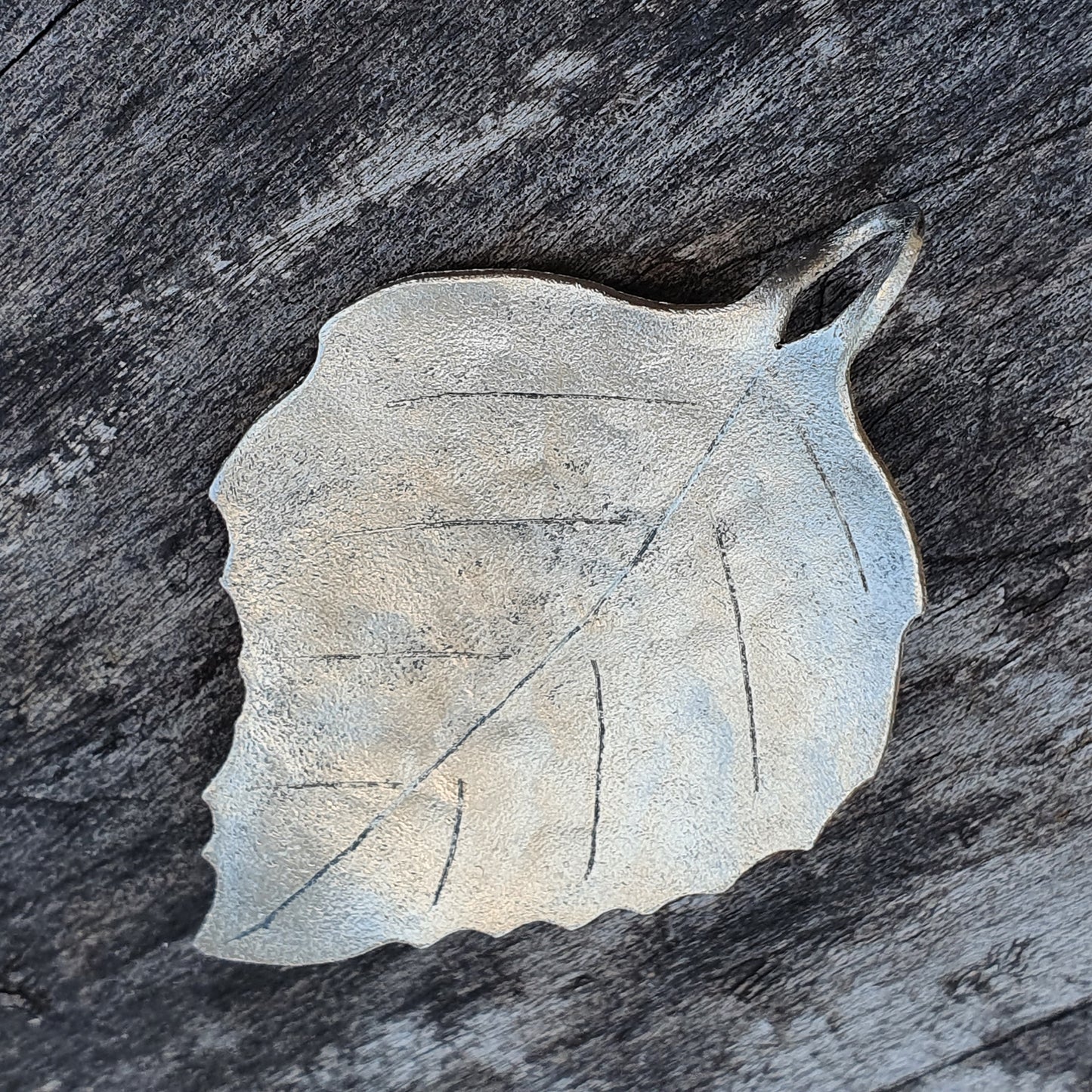 Leaf-shaped ceramic or concrete decorative object with vein-like texture.