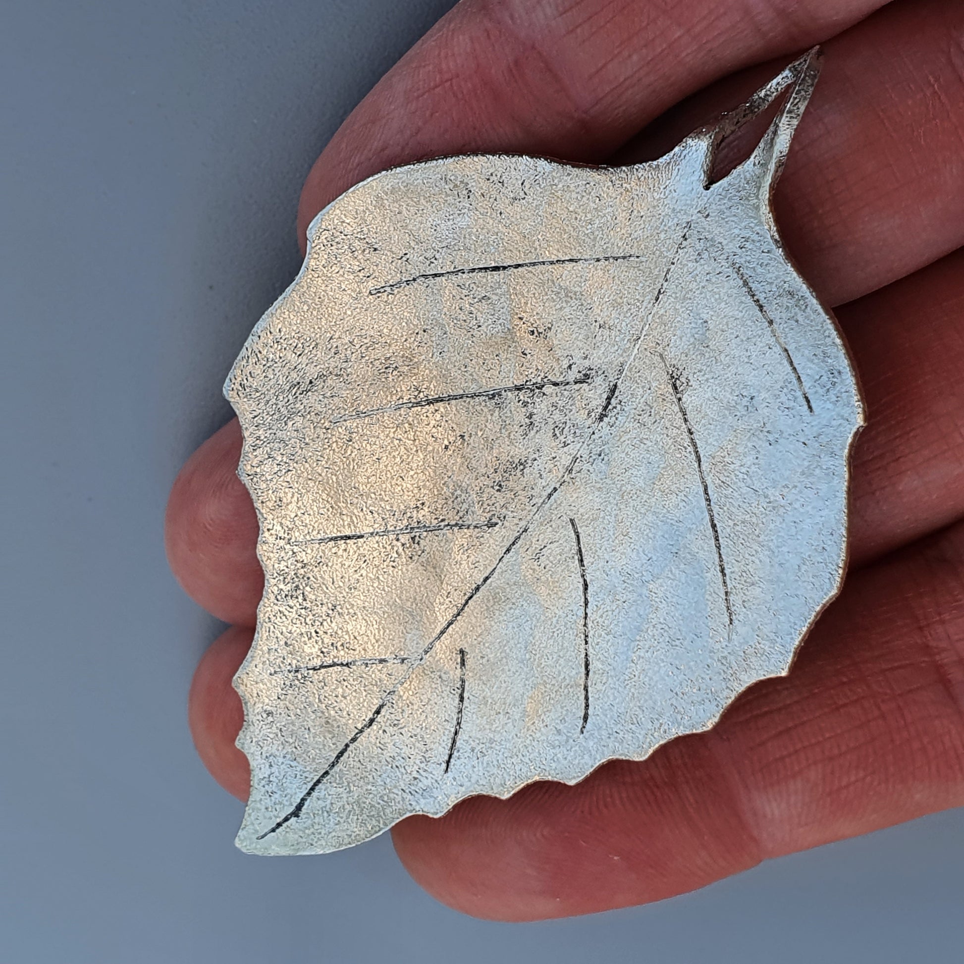 Delicate white ceramic leaf with visible veins and texture.