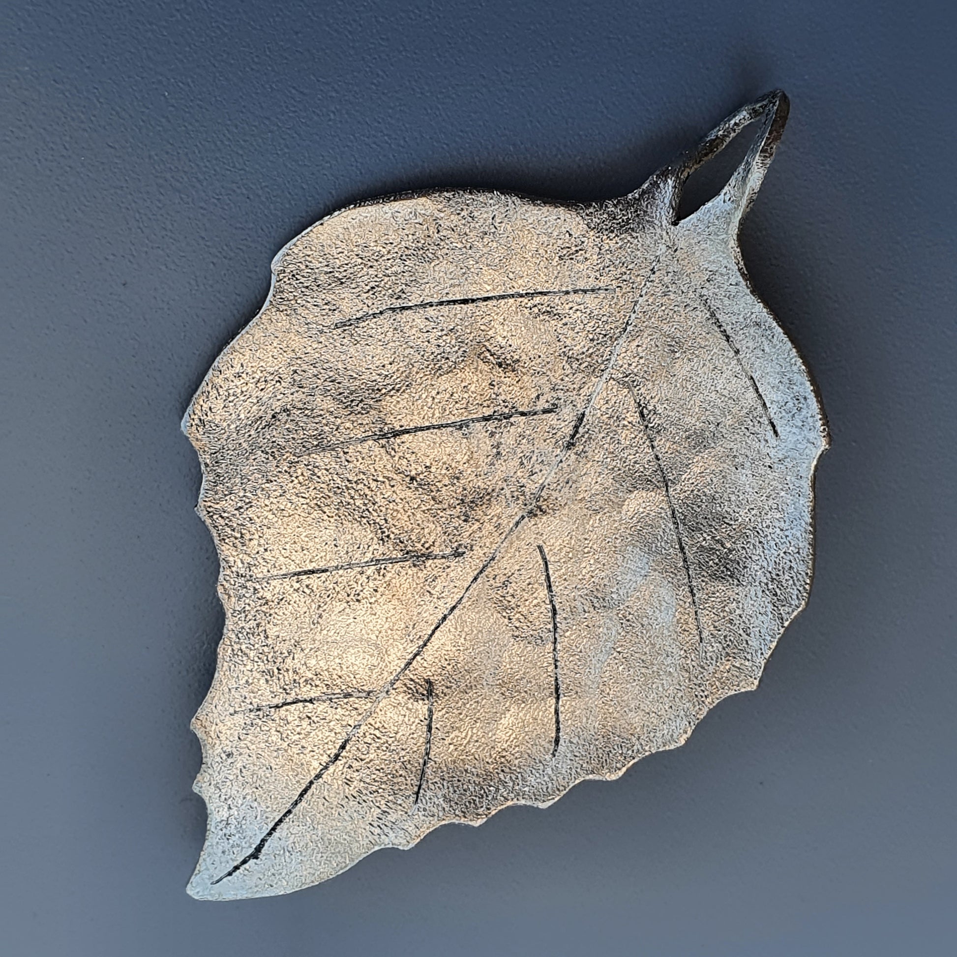 Textured ceramic or stone leaf with visible veins and a pointed tip.