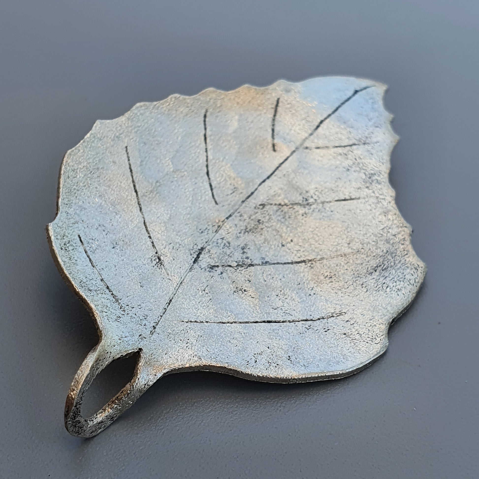 Ceramic or clay leaf-shaped dish with visible veins and a pale, textured surface.