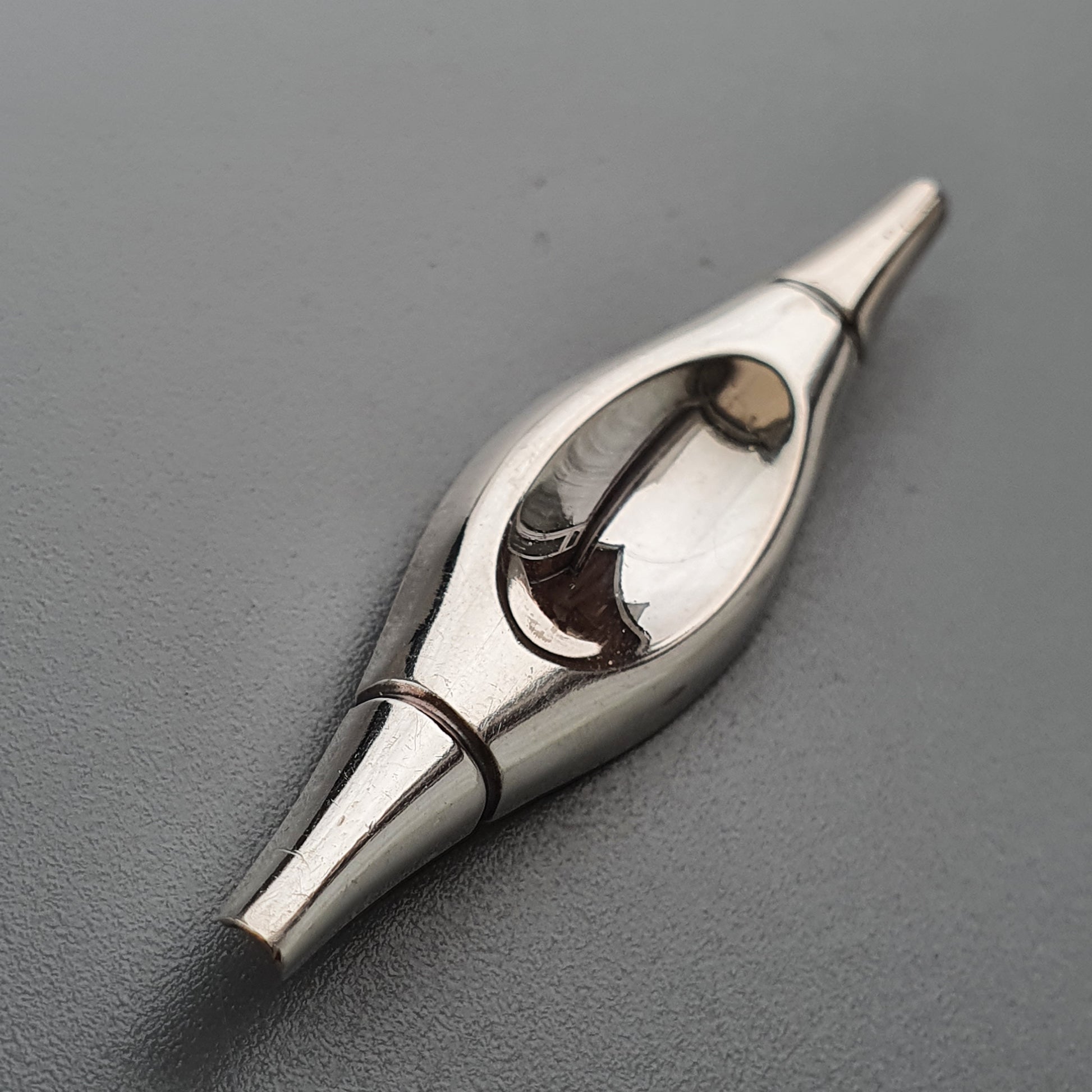 Metallic calligraphy nib with a curved slit and visible ink reservoir.