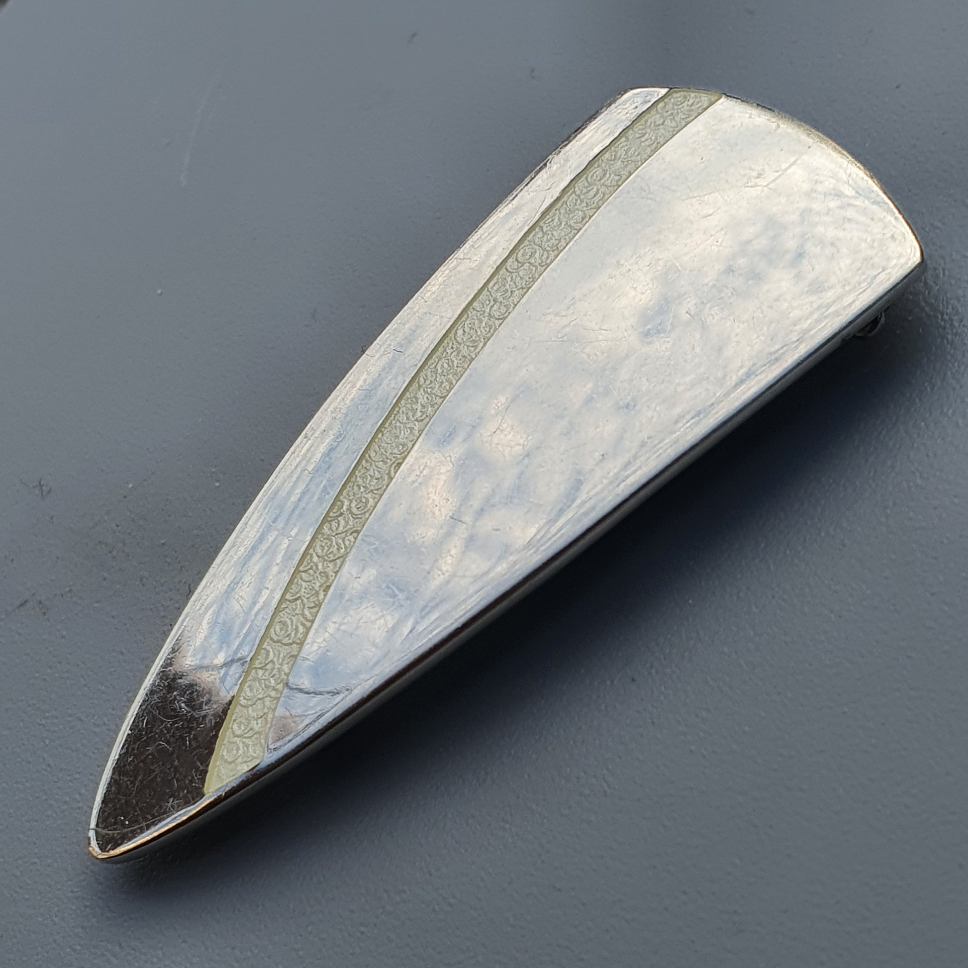 Elongated teardrop-shaped enamel brooch in silver, white enamel, and dark tip design