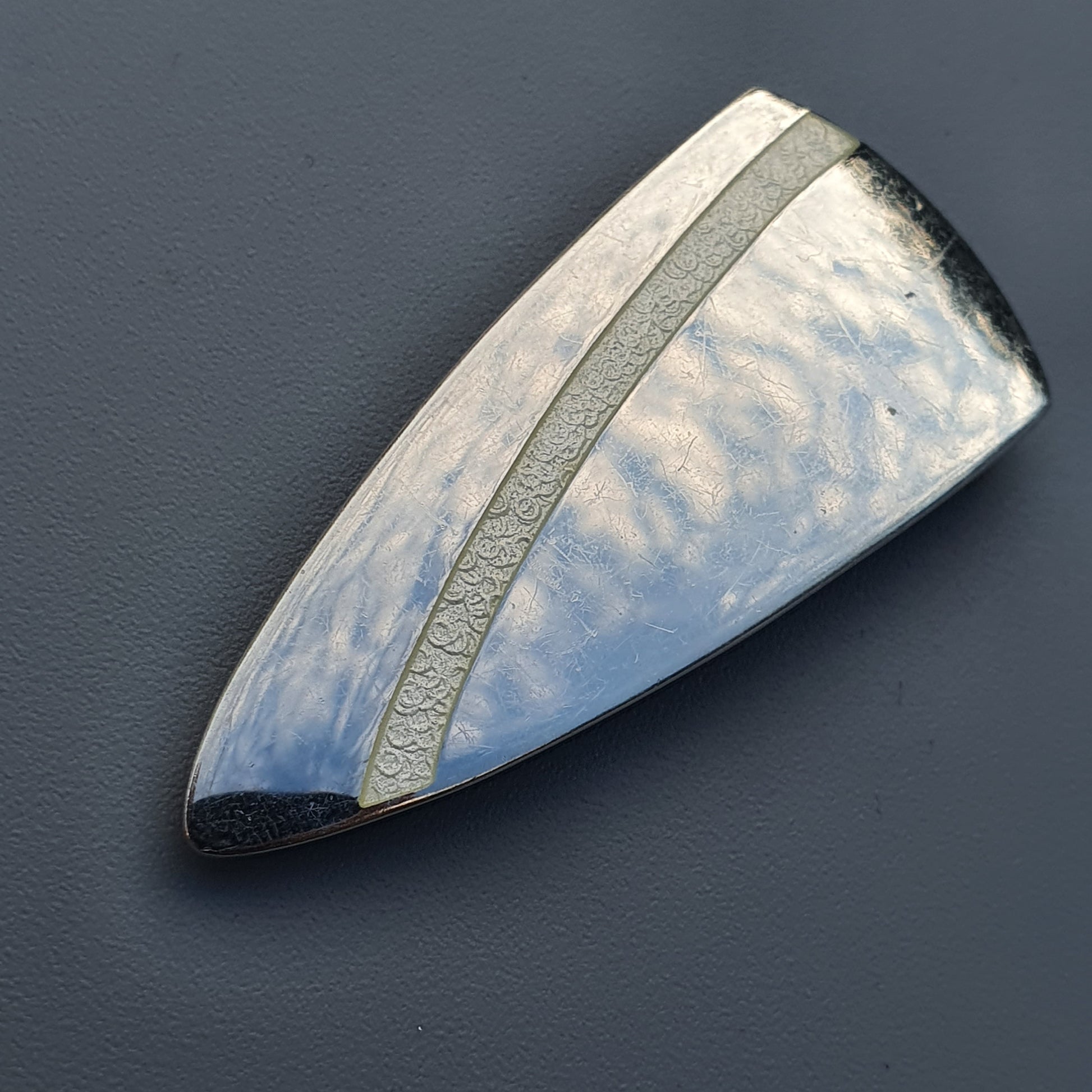 Triangular metallic pendant with hammered surface in Platinoro’s white enamel brooch