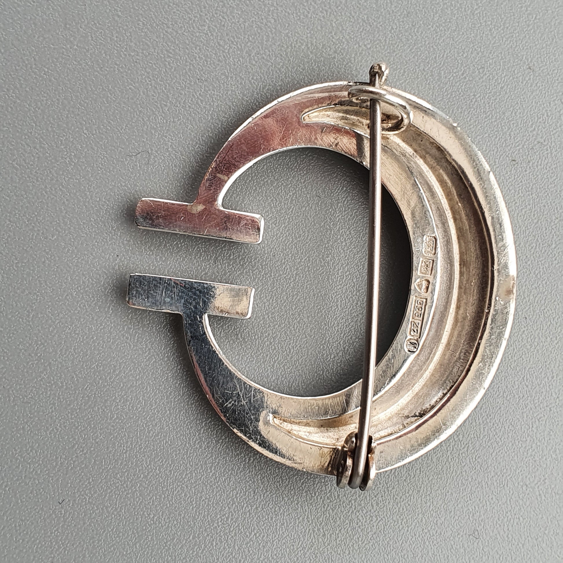 Silver brooch or pin in the shape of a stylized letter G.