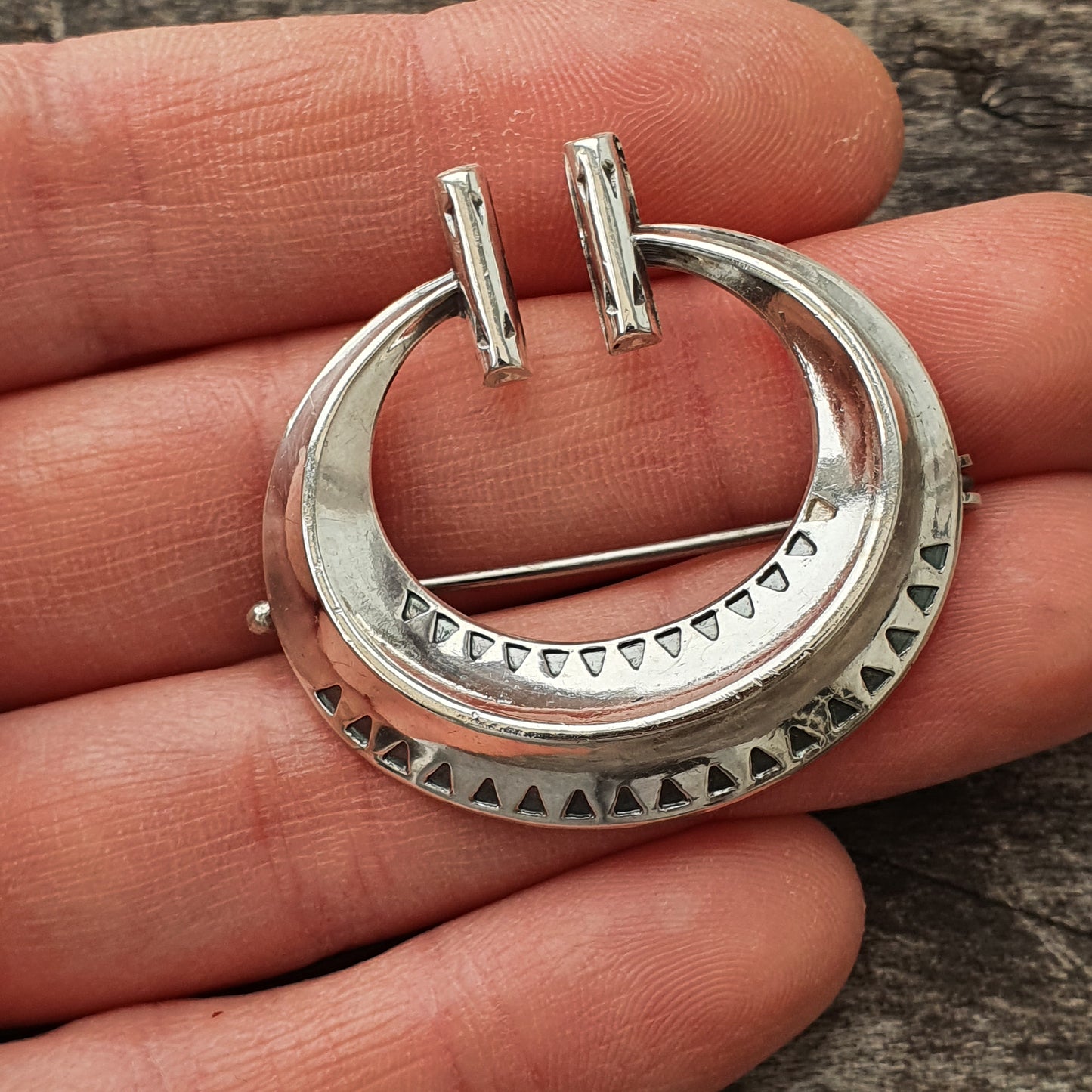 Silver crescent-shaped pendant with geometric patterns and two prongs at the top.