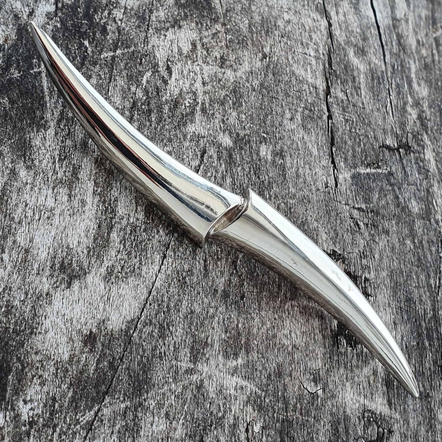 Sleek, curved metal knife with a pointed tip and smooth handle.