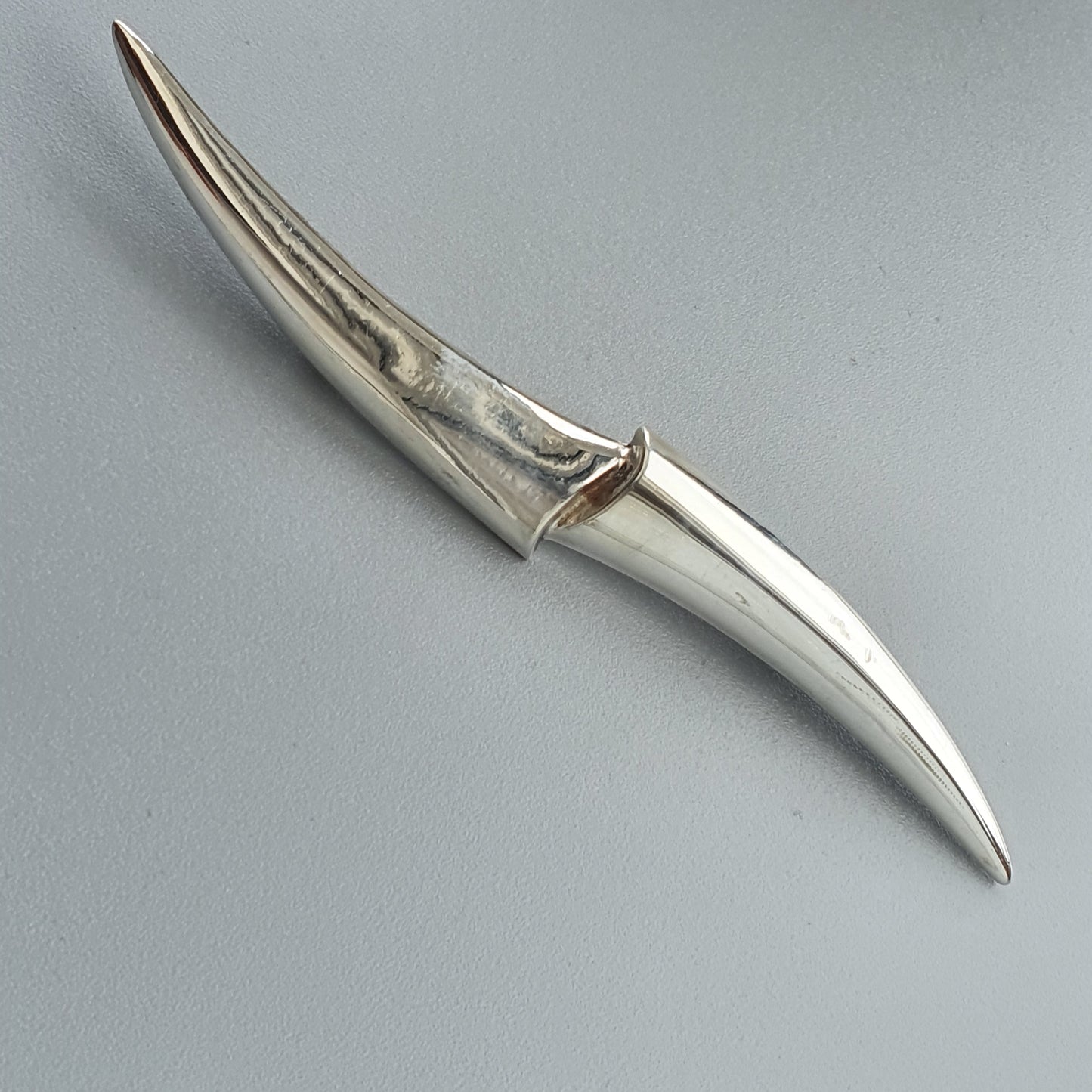 Curved, metallic blade or dagger with a distinctive ribbed handle.